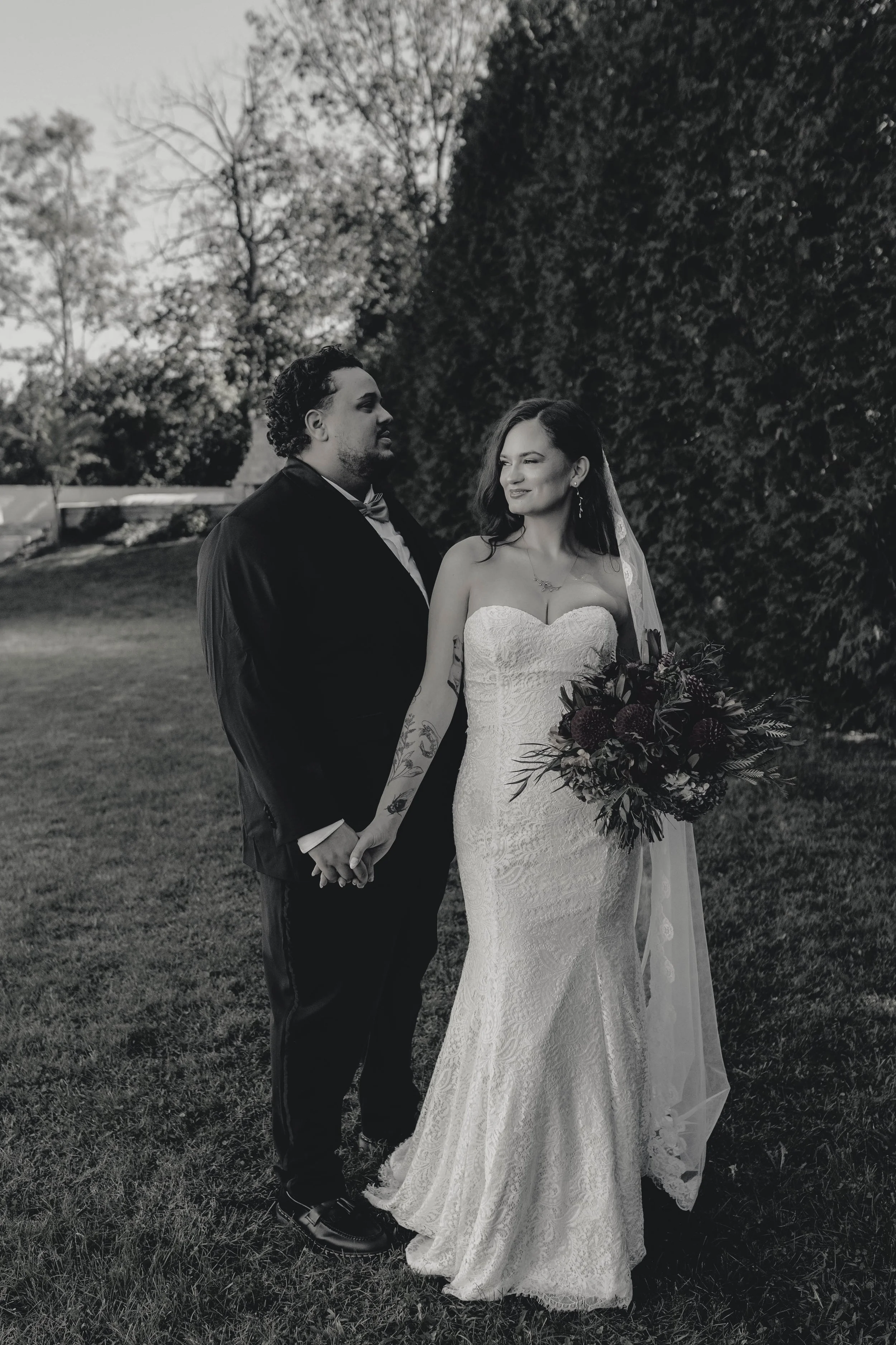 A black and white photo of a bride and groom holding hands outdoors at historic wedding venue moundale manor in winchester kentucky
