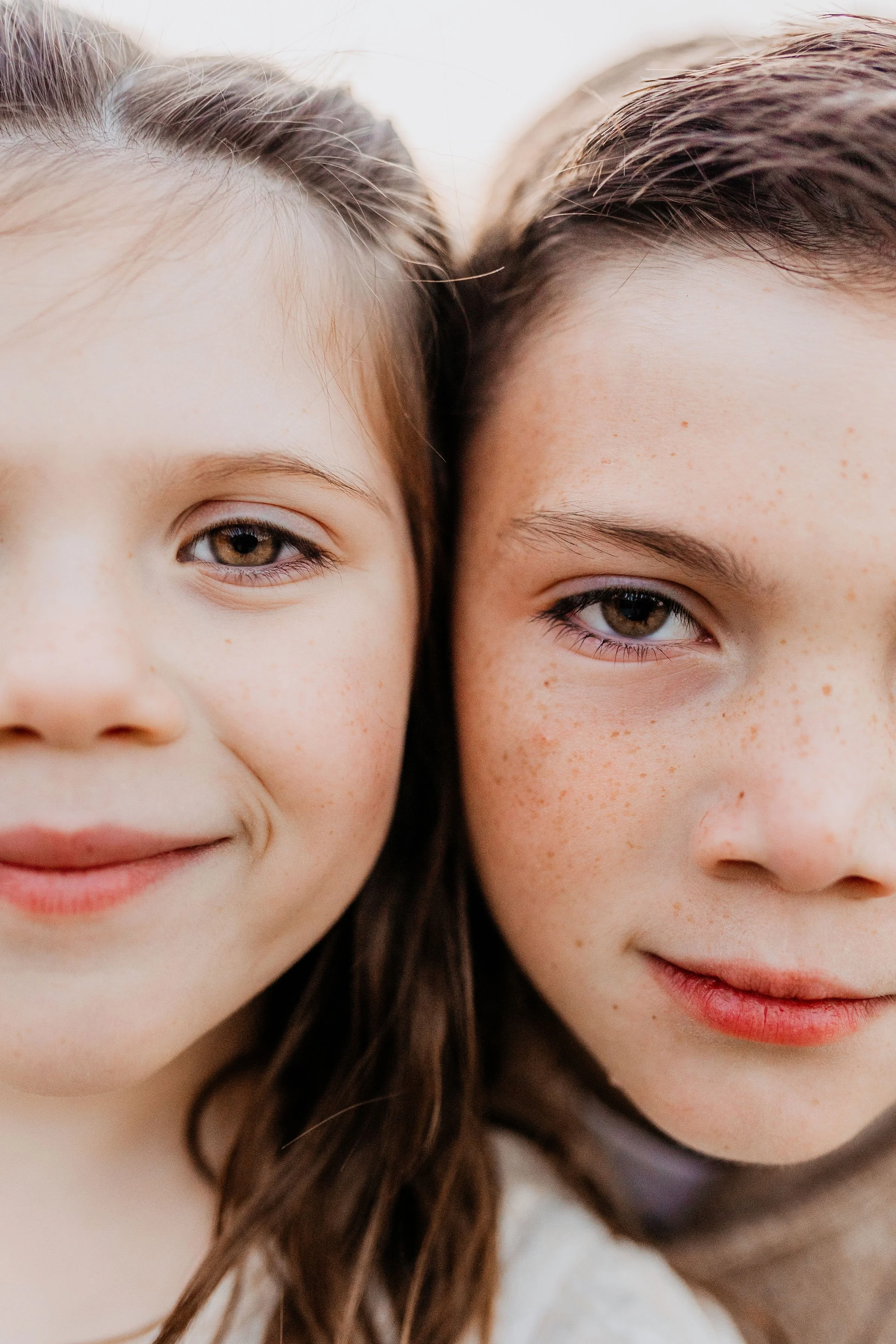 Close-up of two girls with similar features, smiling, and showing their faces close together. lexington kentucky family photographer storytelling portraits