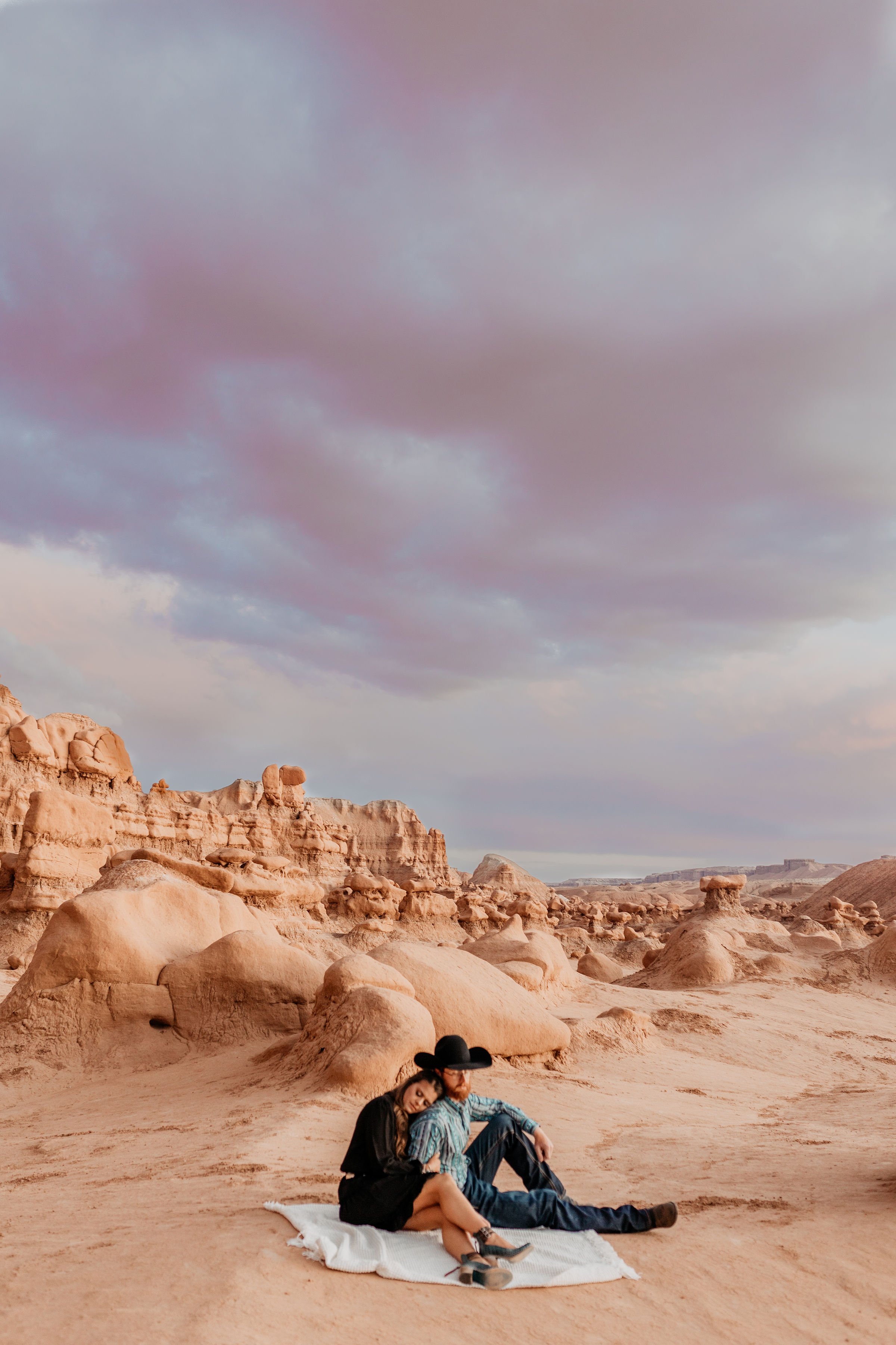 couple sitting on a blanket in goblin valley state park utah for elopement