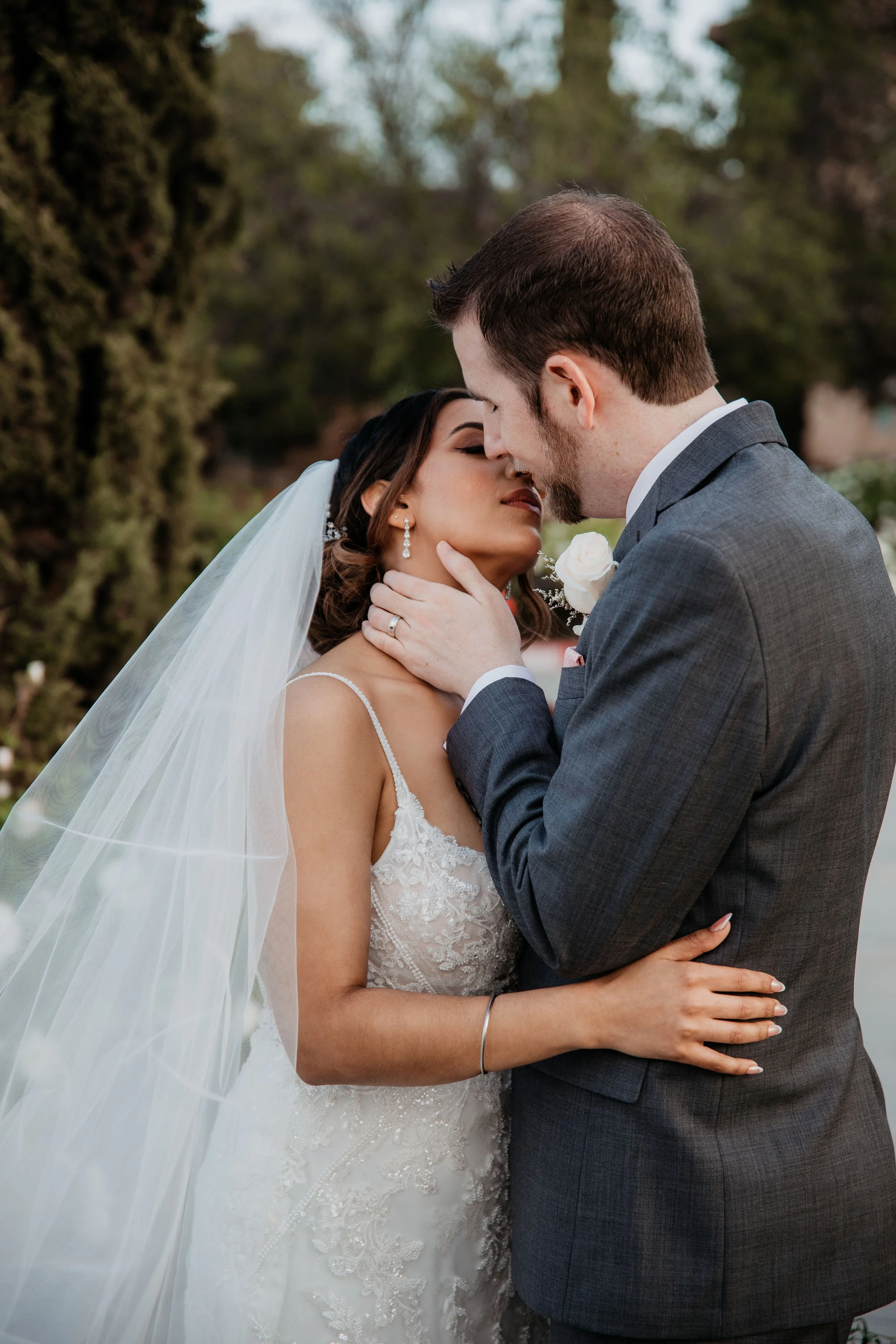 A bride and groom share a romantic moment outdoors, with their foreheads and noses touching san diego california wedding