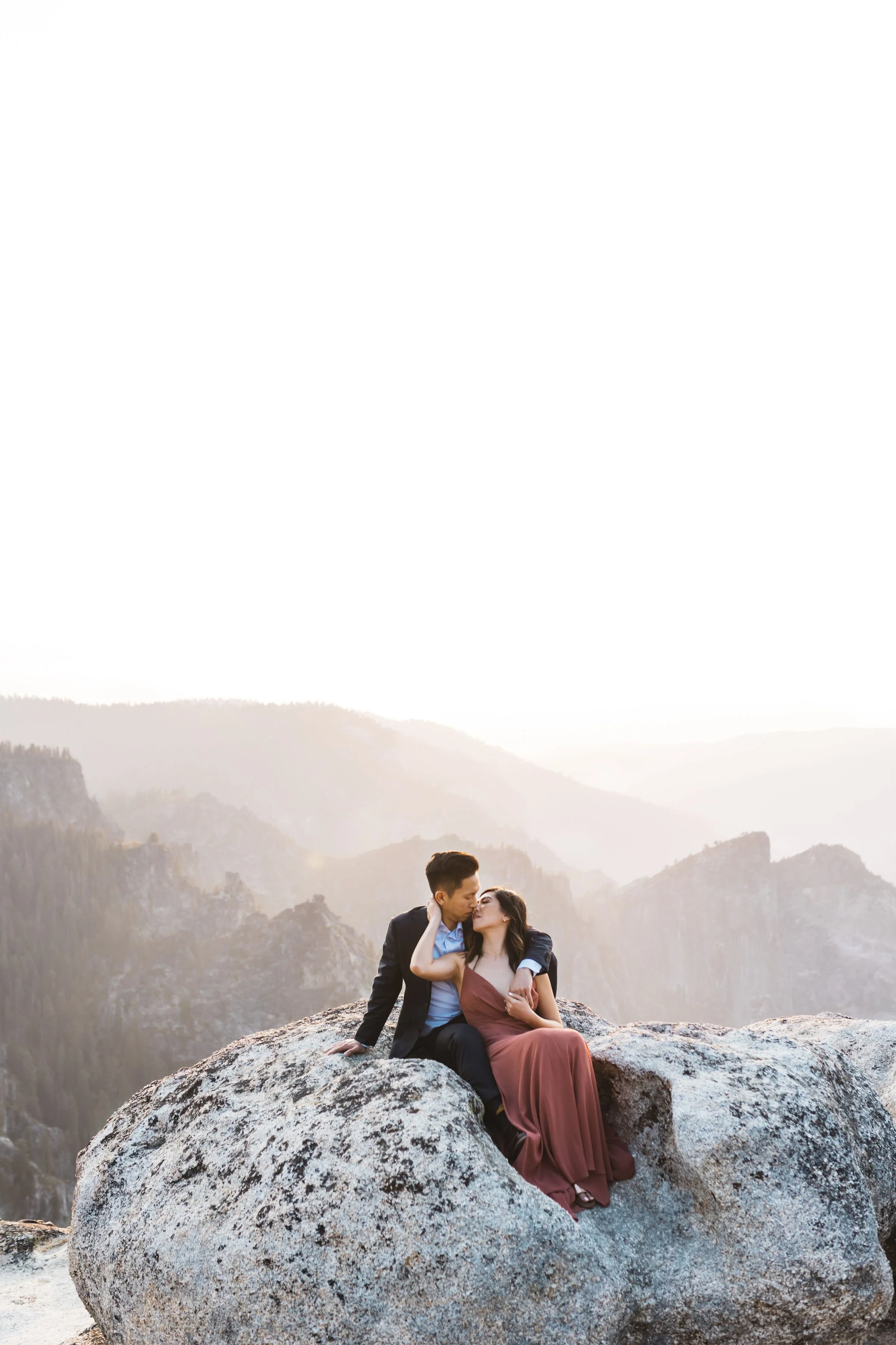 Yosemite National Park Elopement photo at taft point. the couple are sitting on a rock with a view of yosemite at sunset