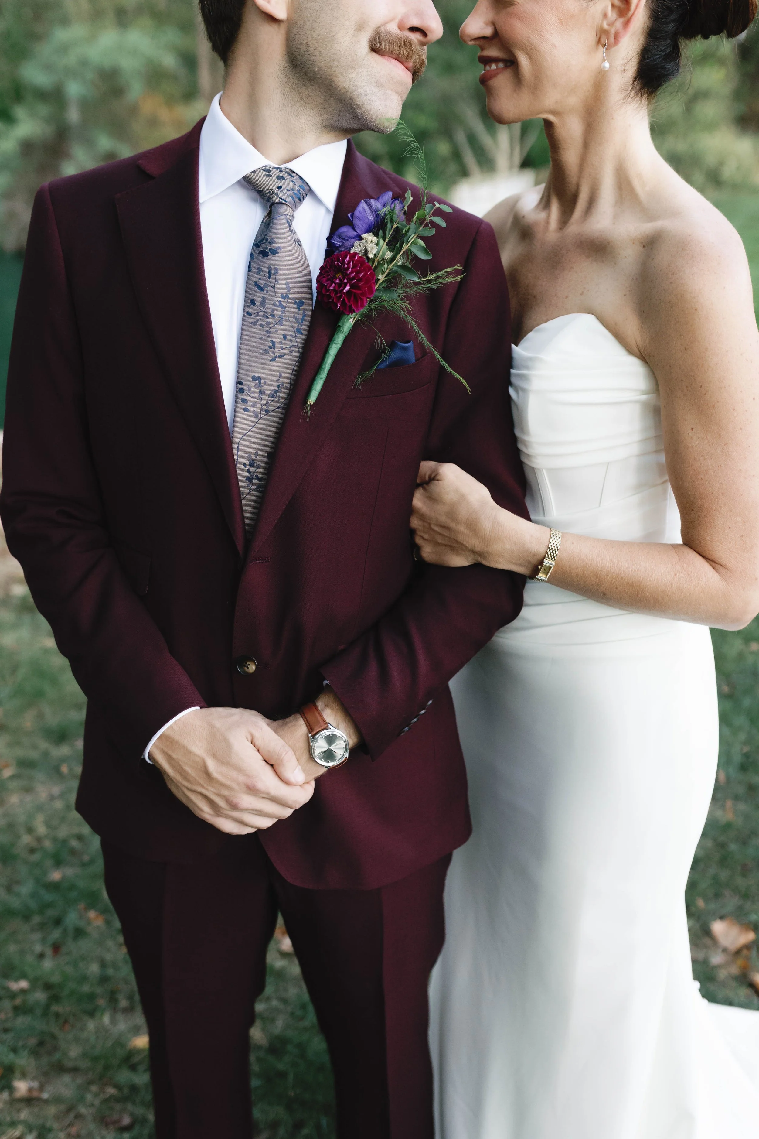 Close-up photo of a newlywed couple, with the bride holding onto the groom's arm, both smiling. elegant kentucky garden wedding 