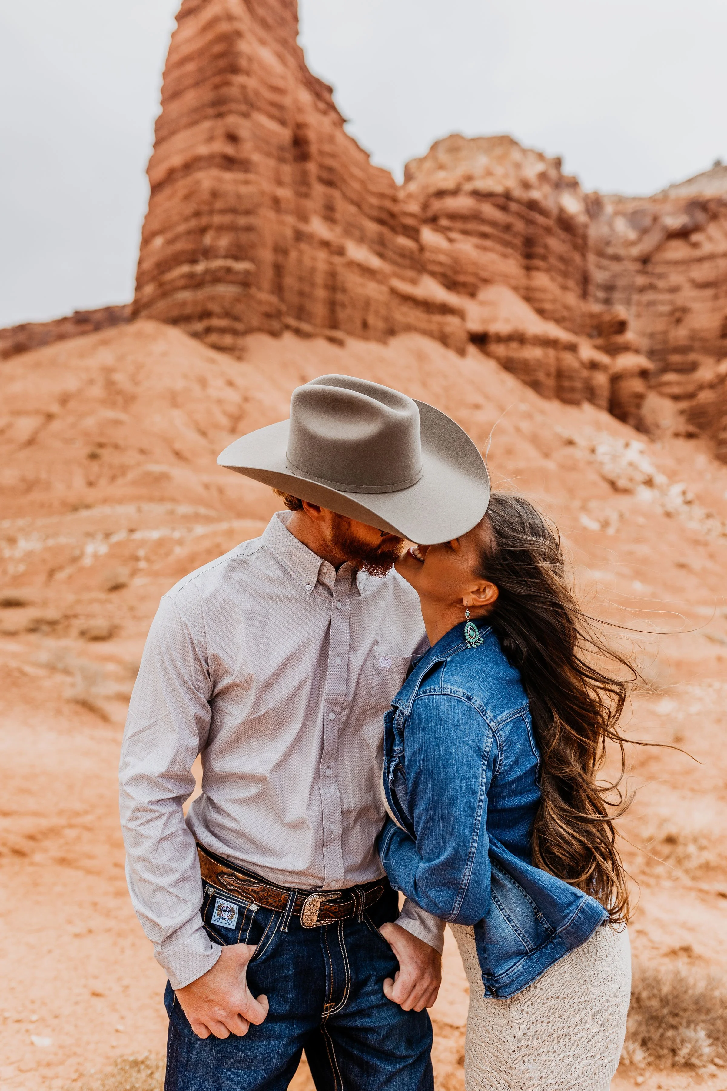 A couple sharing a kiss in a desert landscape with red rock formations in capitol reef national park utah elopement