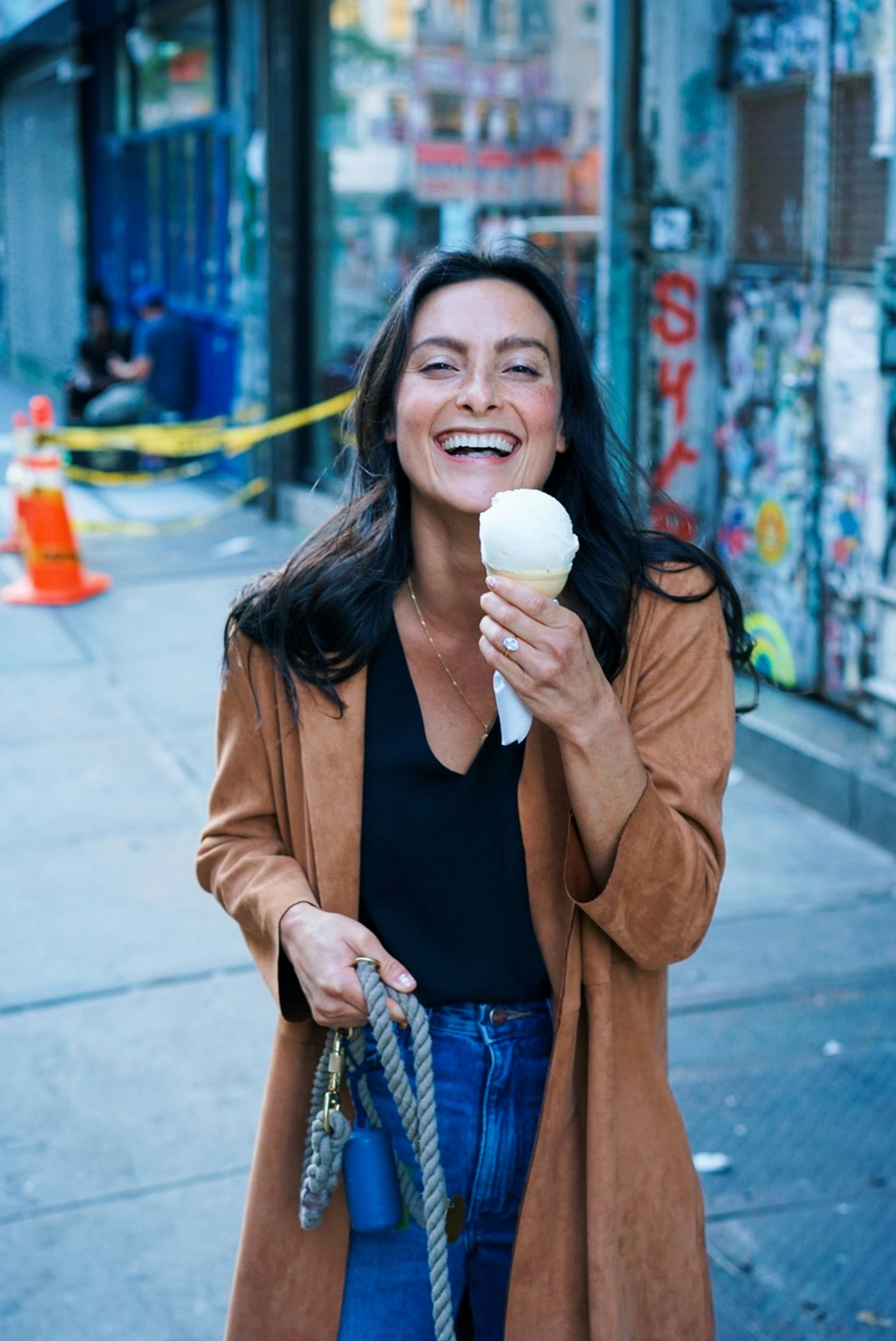 Woman smiling while holding ice cream, representing The TMJ Relief Center's explanation of causes and symptoms of TMJ in Long Island, NY