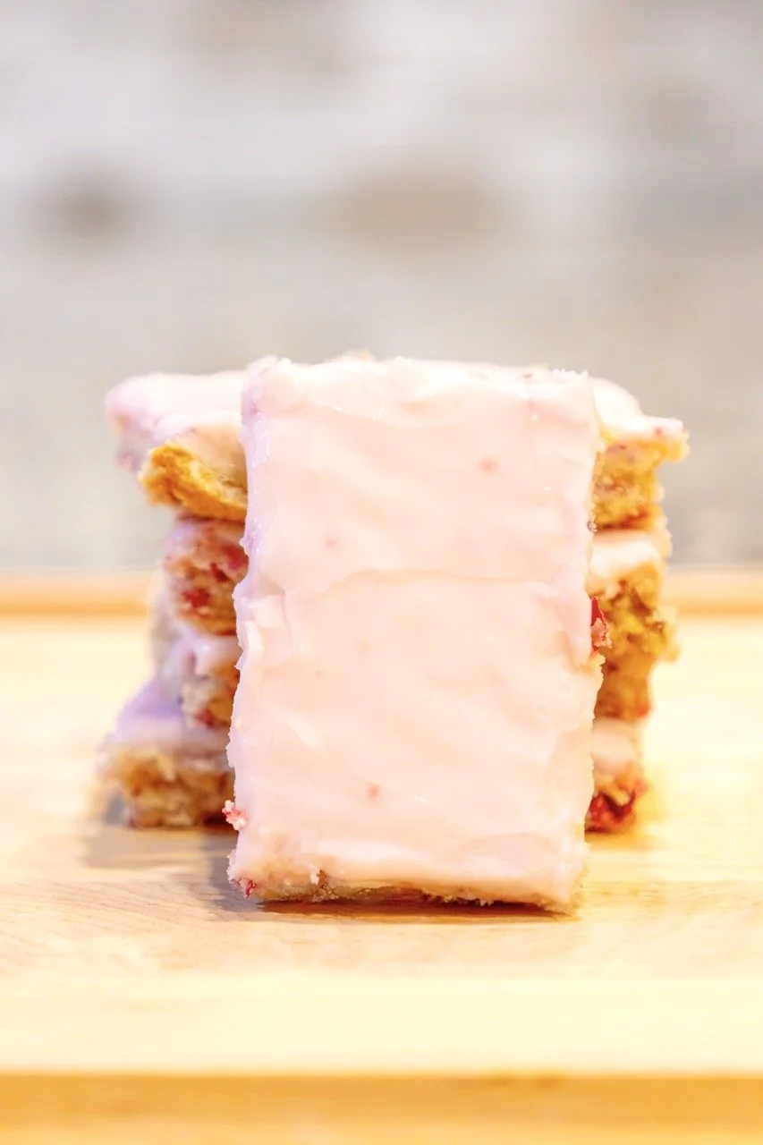 Stacked cookies with pink icing on a wooden surface