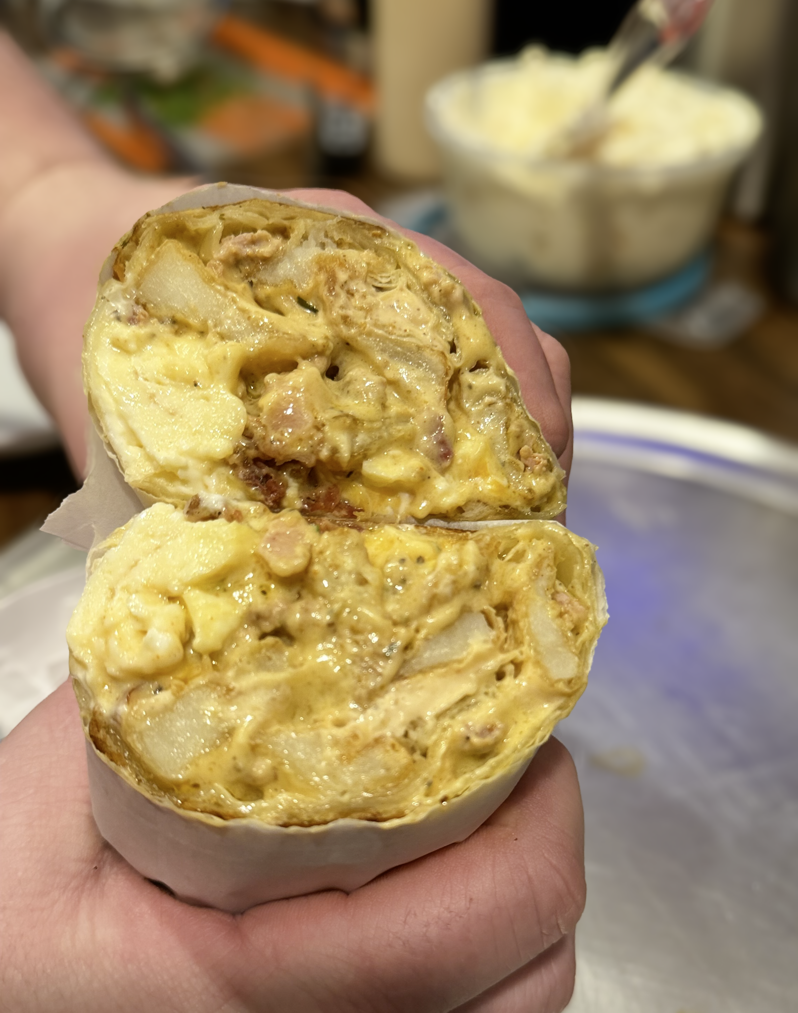 Halved breakfast burrito filled with eggs, cheese, and sausage.