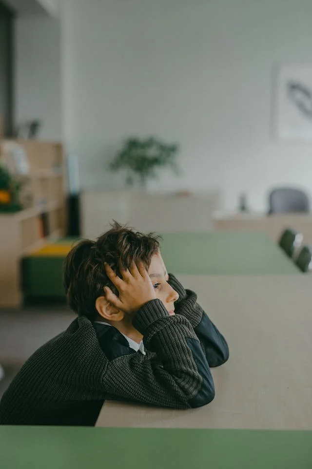A child at his desk with hands in his hair