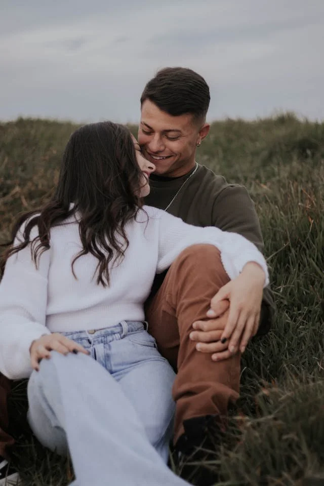 A couple smiling sitting down outside