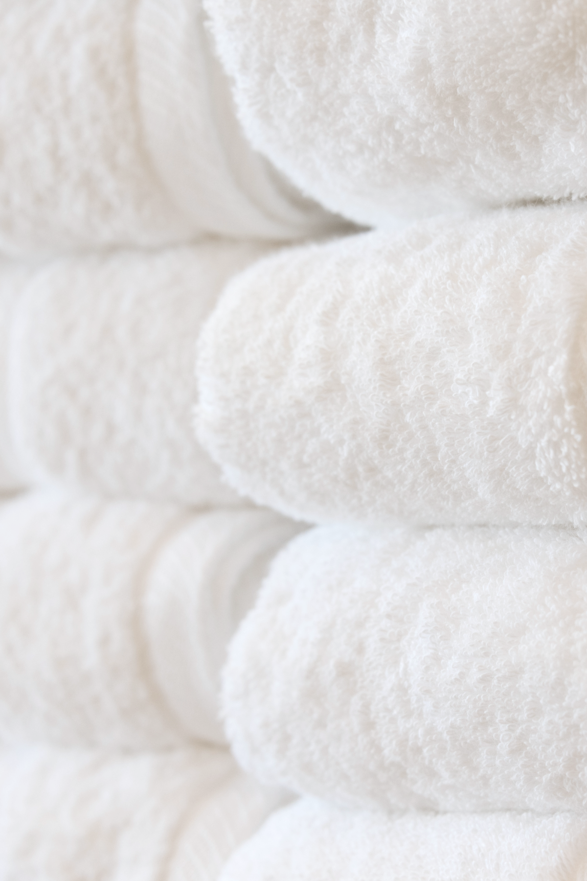 Stacked clean, white towels with textured surface.