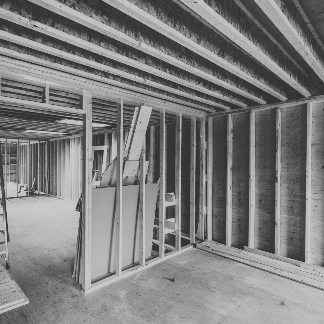 Interior of a building under construction showing wooden framing and ceiling joists.