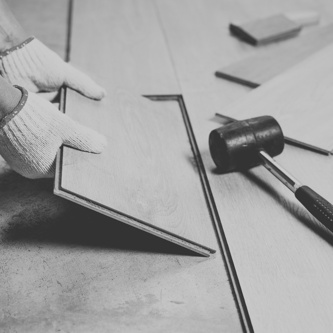 worker using gloved hands to install crown molding on a wooden surface with tools and materials nearby