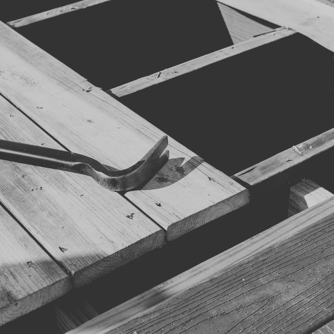 Black and white photo of wooden planks and a crowbar on a construction site.