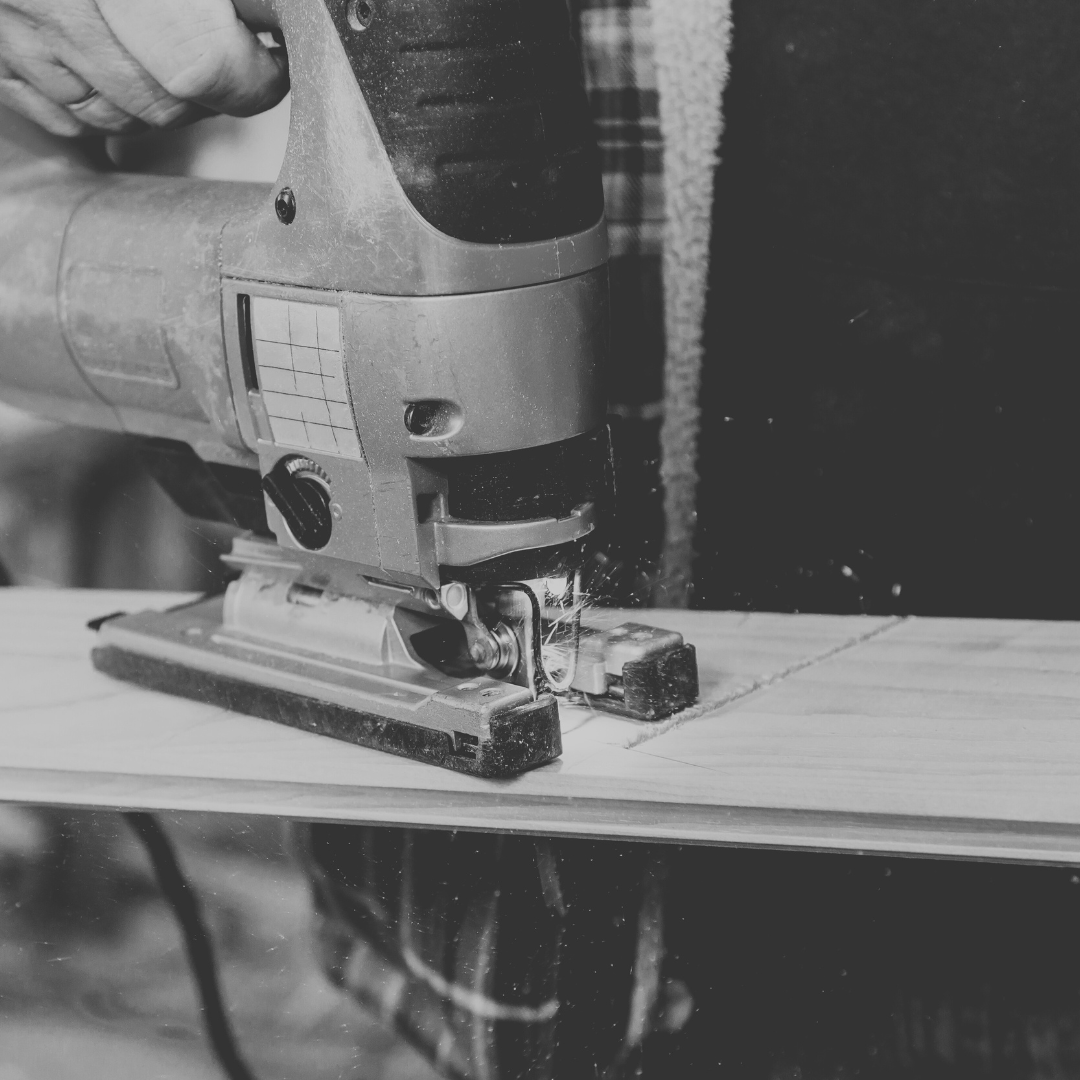 A person using a jigsaw saw to cut a piece of wood.