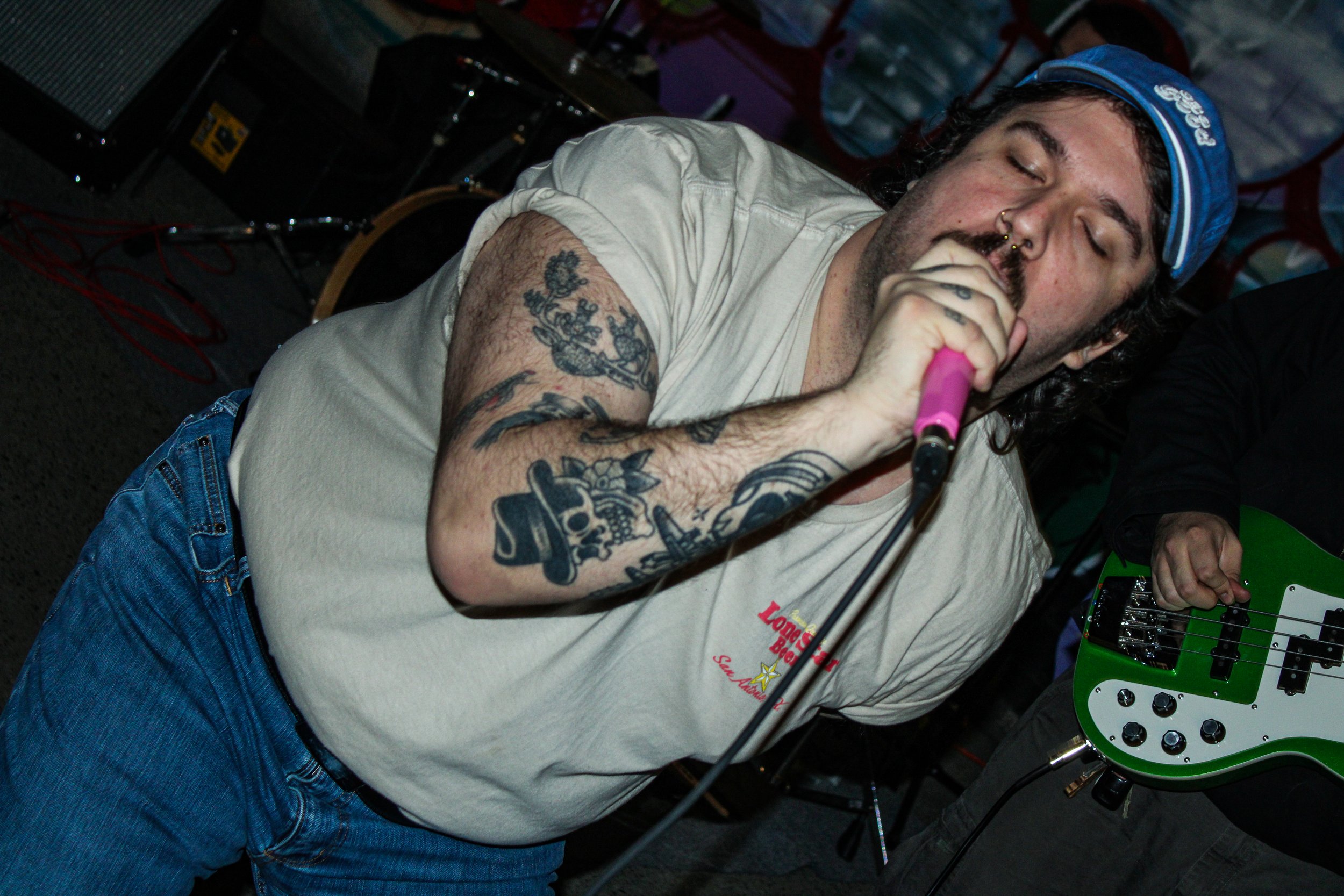 A man with tattoos singing into a microphone at a live music event.