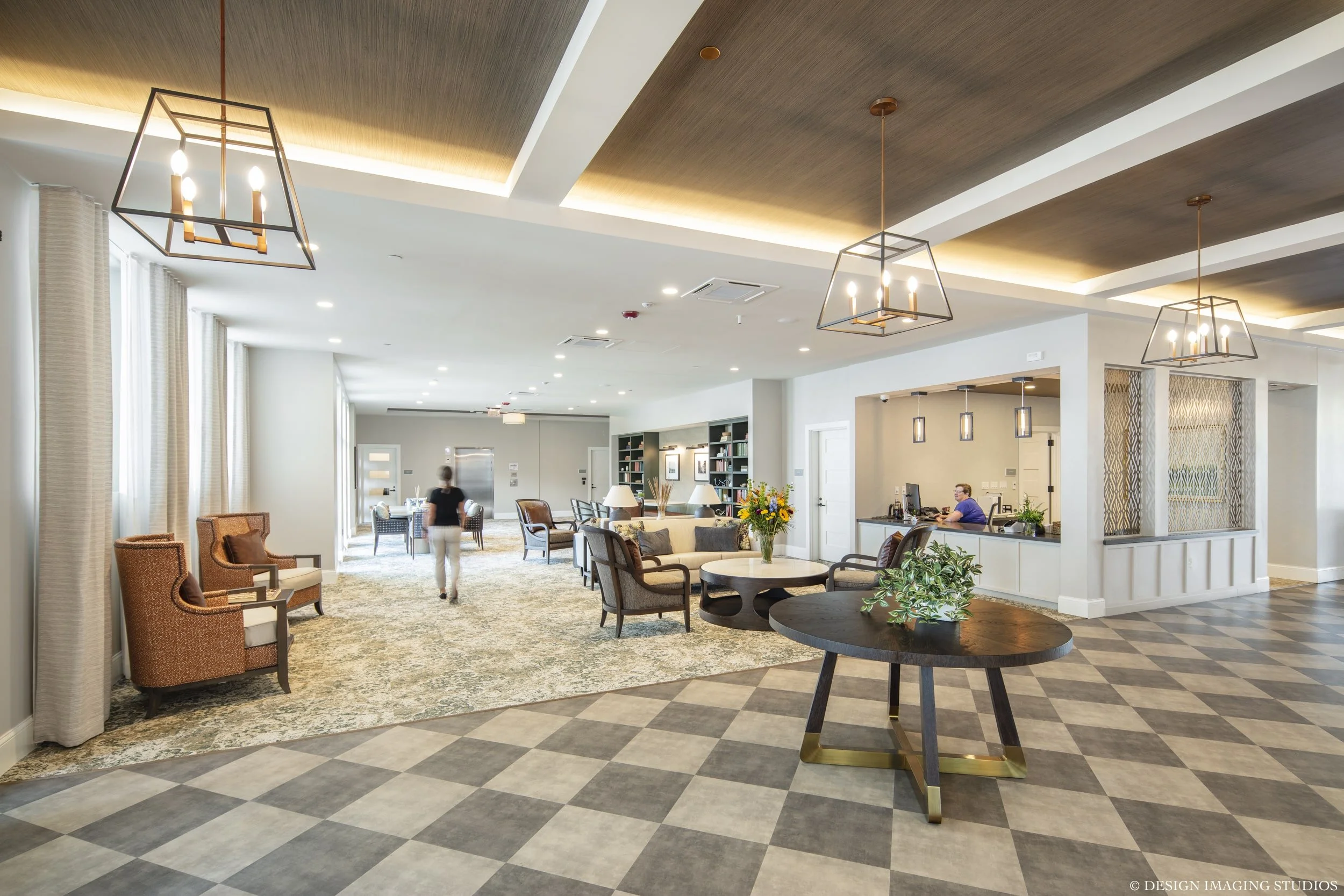 A spacious hotel lobby with seating areas, a reception desk, and decorative lighting fixtures.