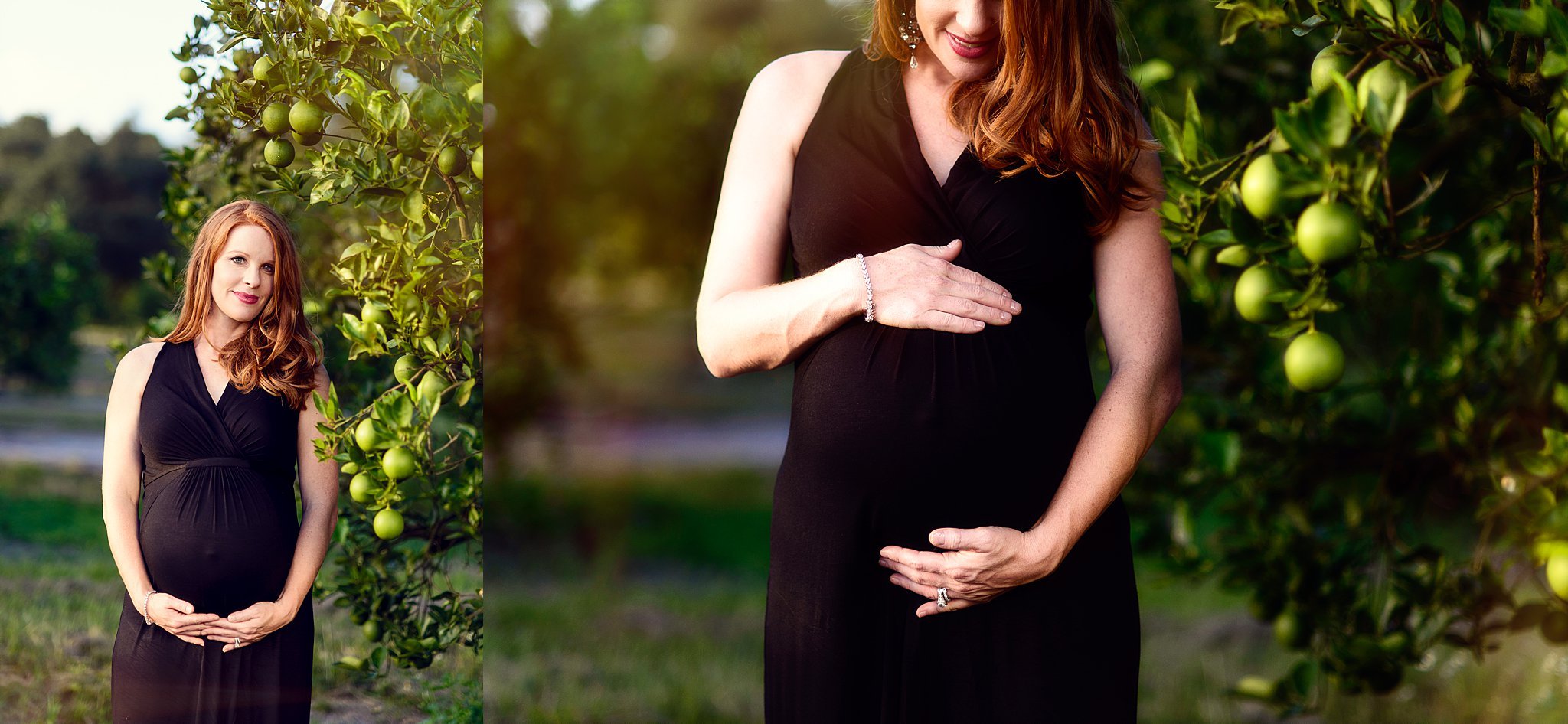 A pregnant woman with red hair in a black dress standing outdoors near a green apple tree, holding her belly with both hands and smiling.