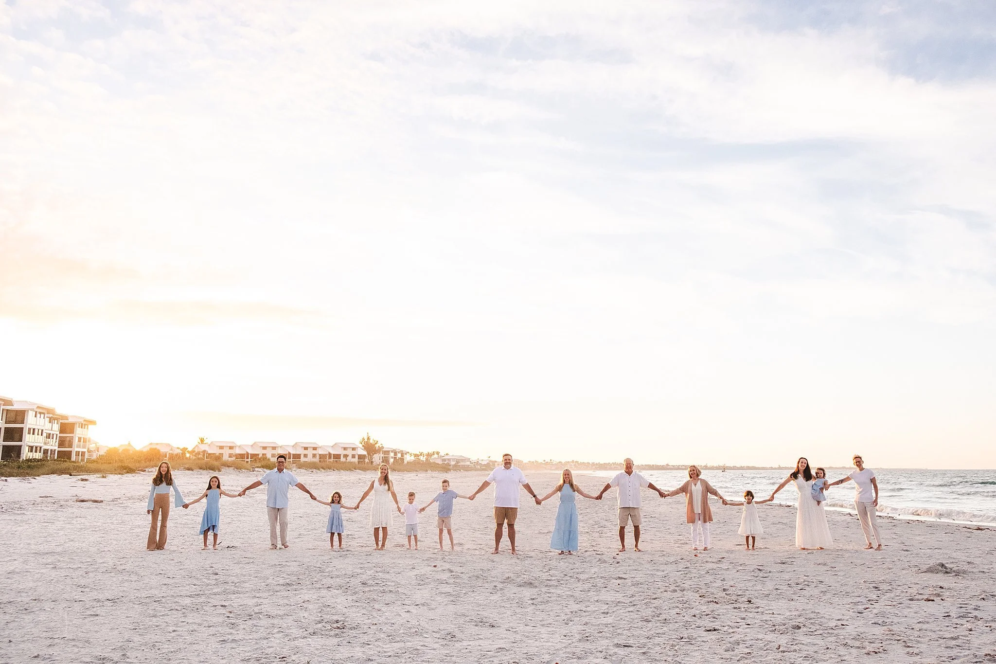 Family holding hands on the beach at sunset