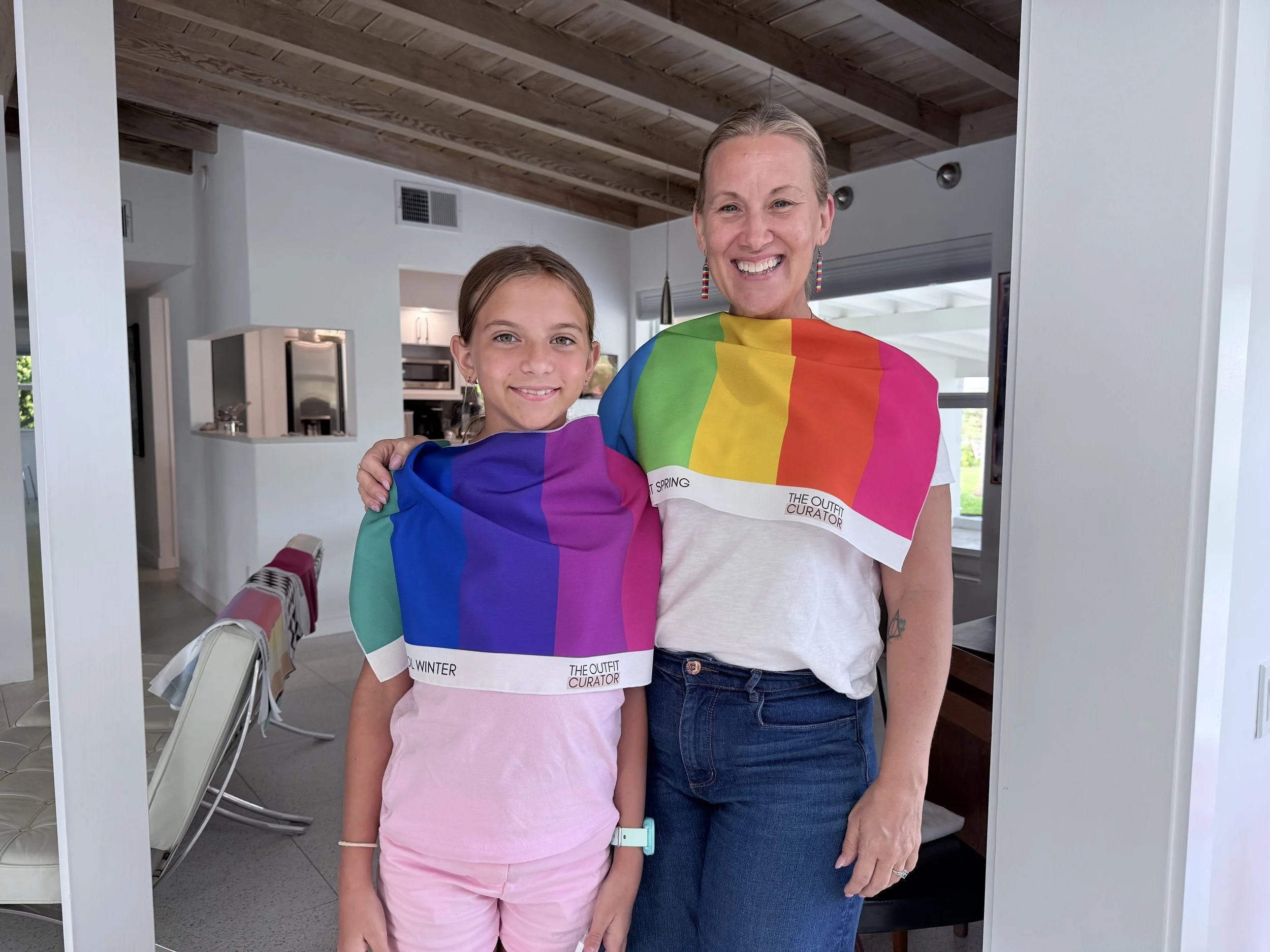 A woman and a girl standing indoors, smiling and wearing Cool Winter and Bright Spring Color Analysis Drapes.