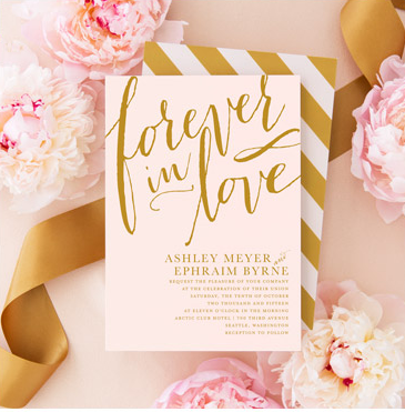 A wedding invitation card with the words 'forever in love' in gold lettering, surrounded by pink and white flowers and gold ribbons.