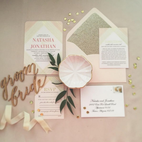 Wedding invitation ensemble with cards, a shell-shaped soap, gold and green confetti, a "groom