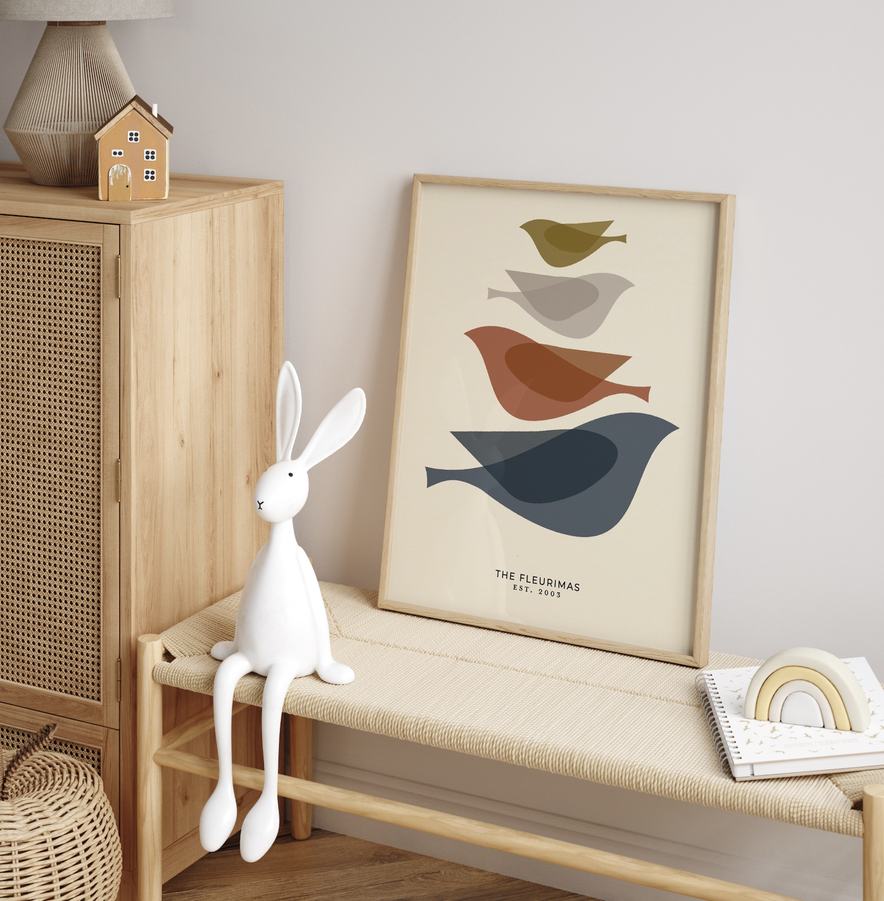 Decorative interior space with a wooden cabinet, a bunny-shaped lamp with long legs sitting on a bench, a framed artwork of colorful birds, and a rainbow-shaped ornament on a book.
