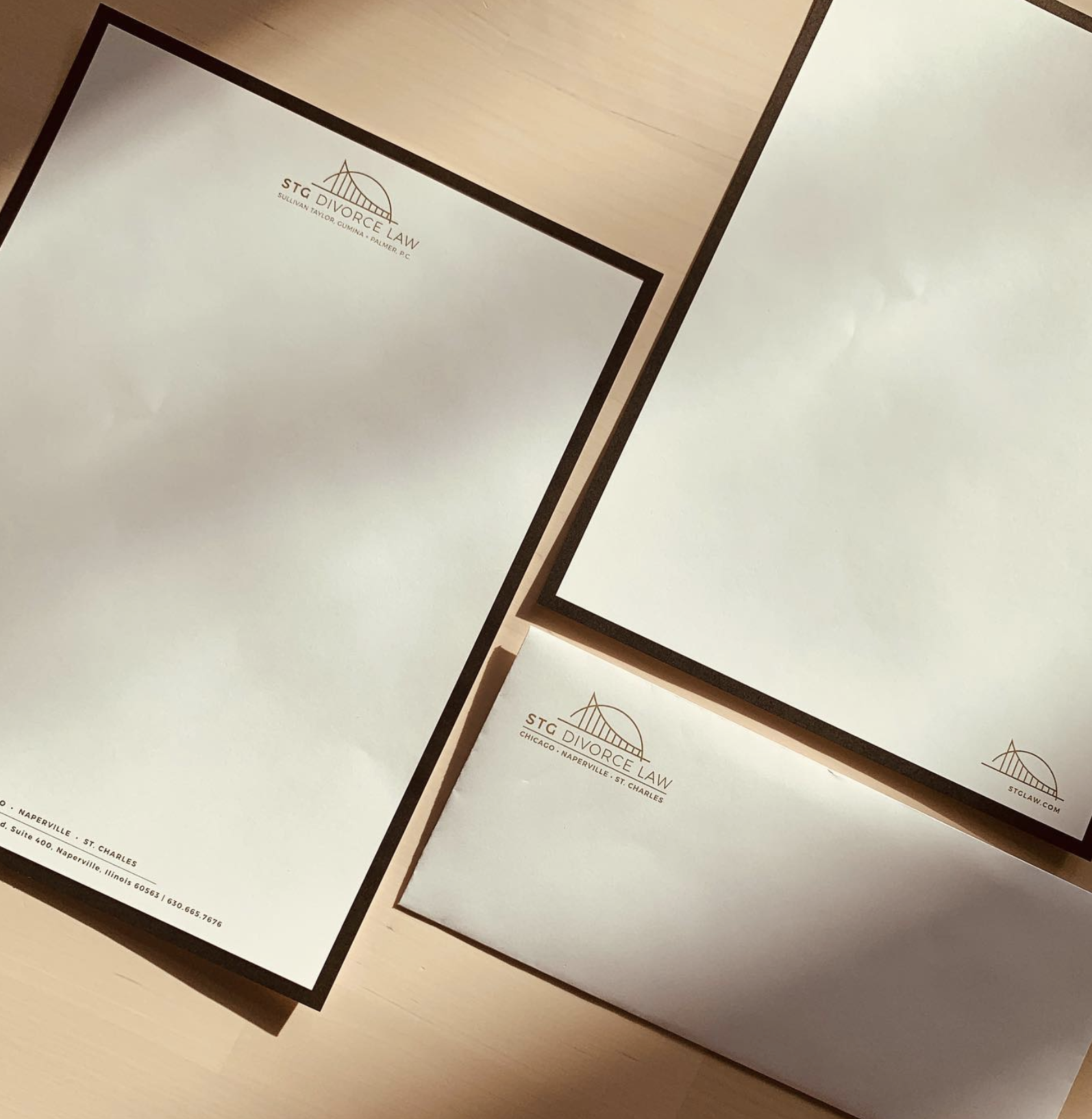 Three legal folders with the STC Divorce Law logo and address, placed on a wooden surface.