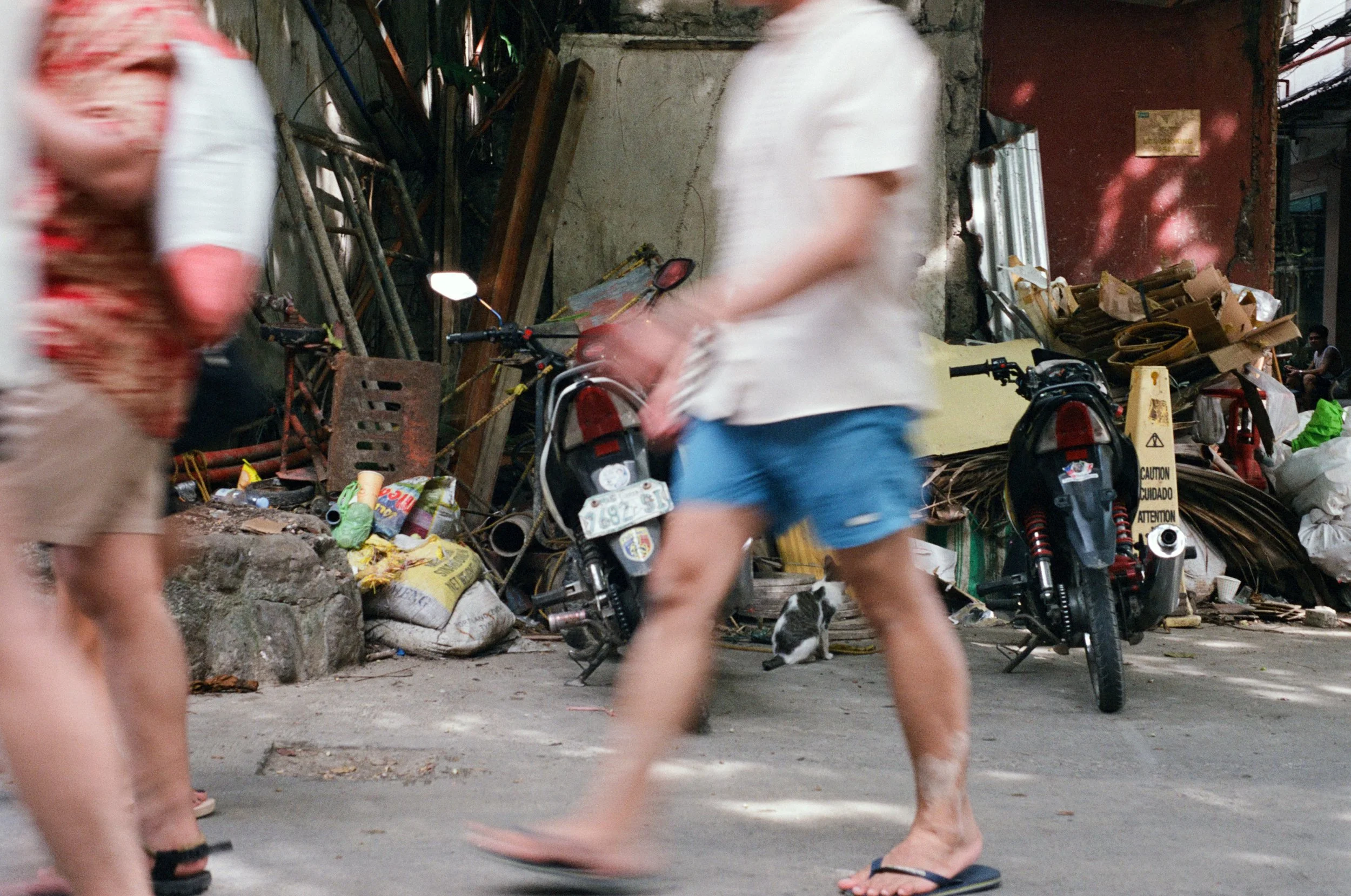 People walking on a street with motorcycles, construction debris, and a rabbit in the background.