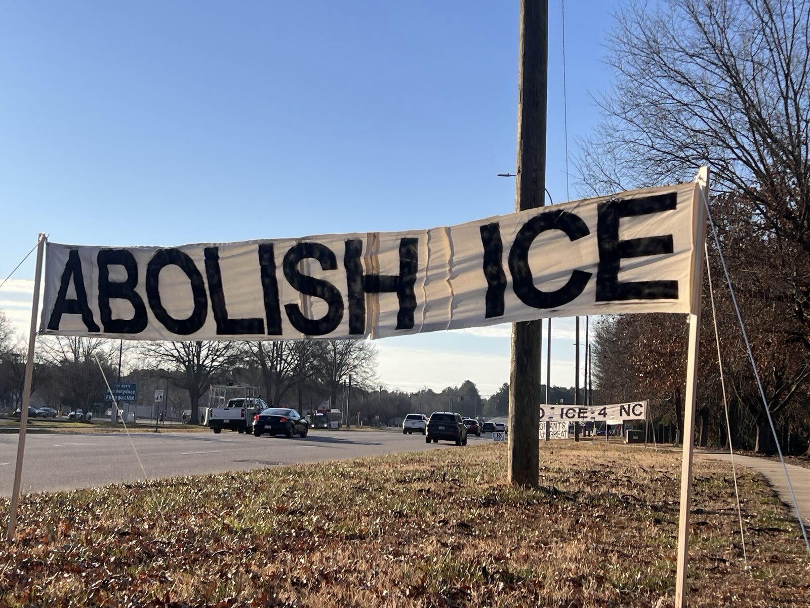 Sign on the side of the road that reads "ABOLISH ICE."