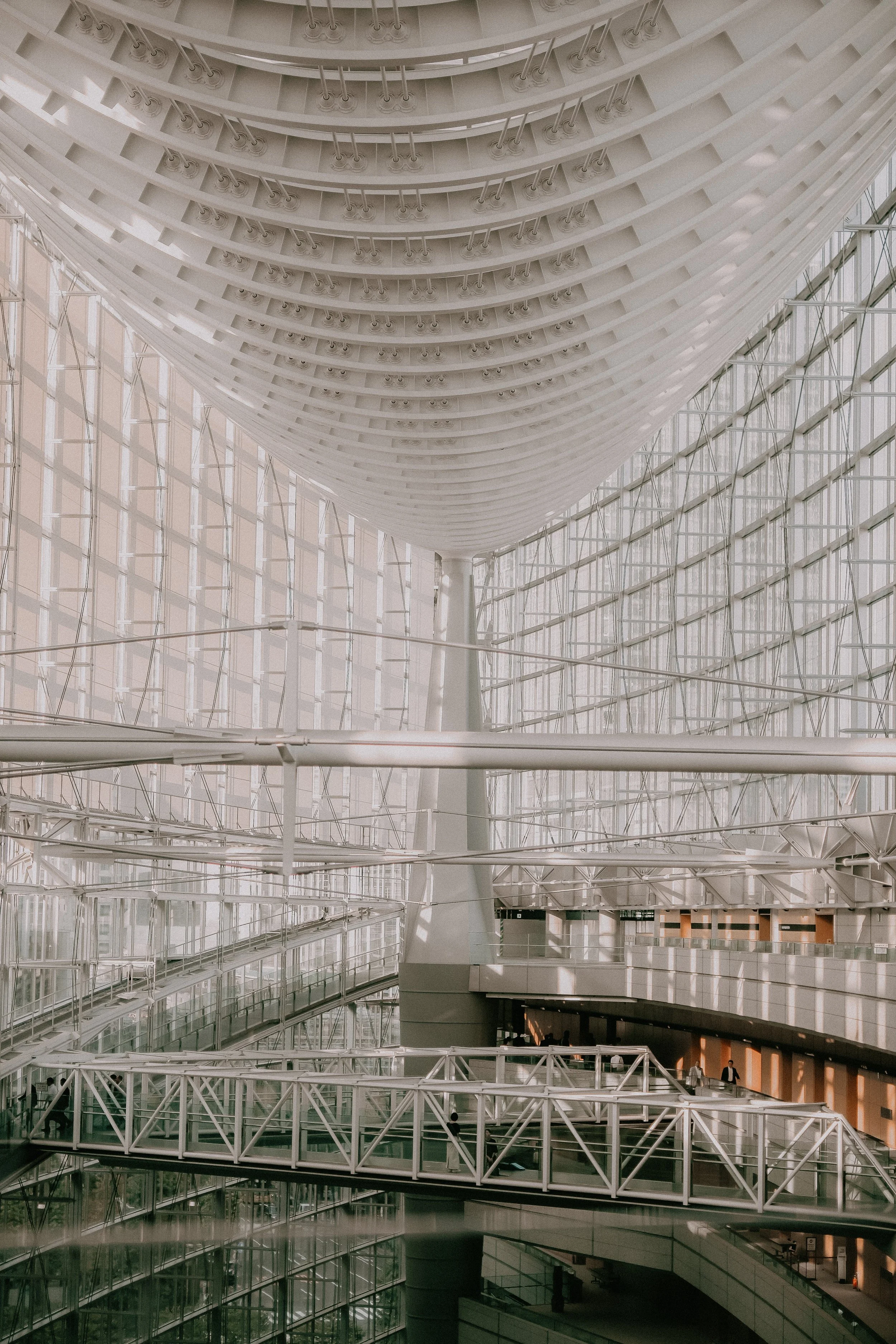 Interior view of a large modern building with glass walls, high ceilings, and multiple walkways and bridges inside.