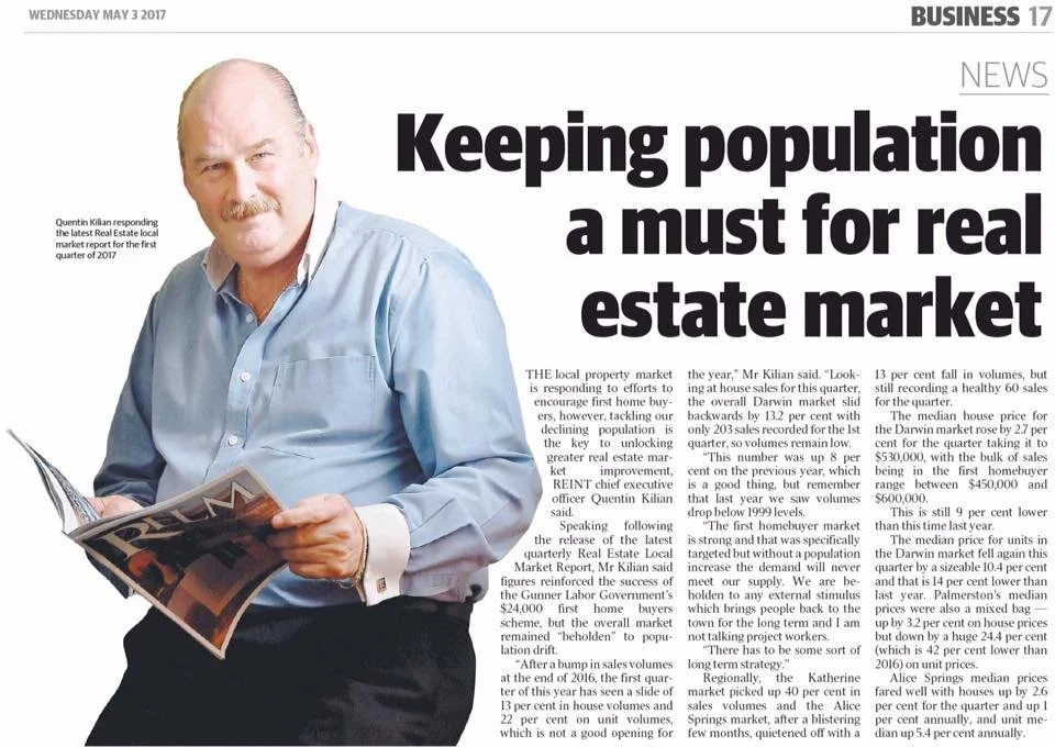 Man with a mustache and light blue shirt reading a magazine or newspaper.