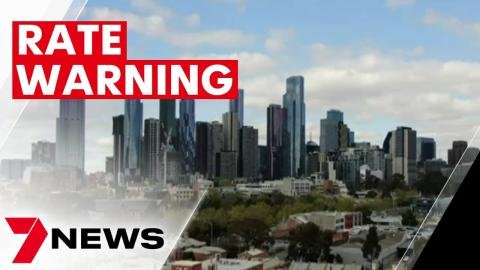 City skyline with tall buildings against a partly cloudy sky, overlaid with a red and white "RATE WARNING" banner and a "7 NEWS" logo in the bottom left corner.