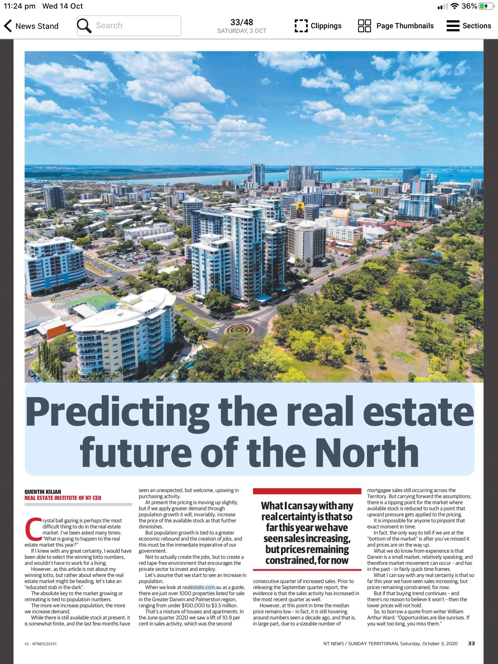 Aerial view of a cityscape with tall modern buildings, green parks, and a waterfront in the background under a partly cloudy sky.