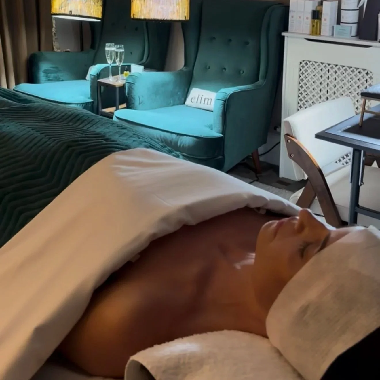 Woman relaxing on a treatment bed with turquoise pedicure chairs behind her at Take Time, Cannizaro House, Wimbledon.
