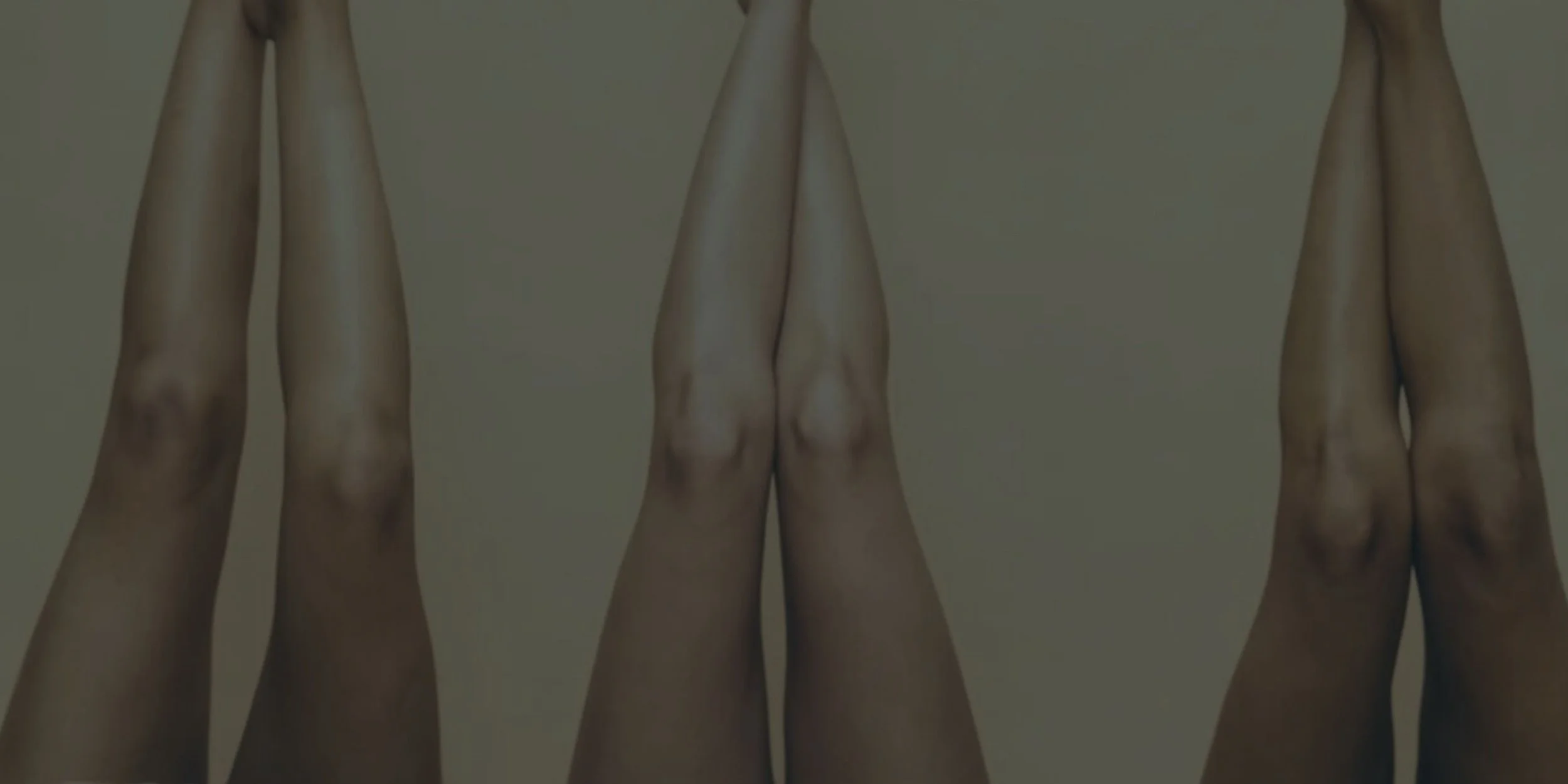 Three pairs of legs pressed together, against a plain background.