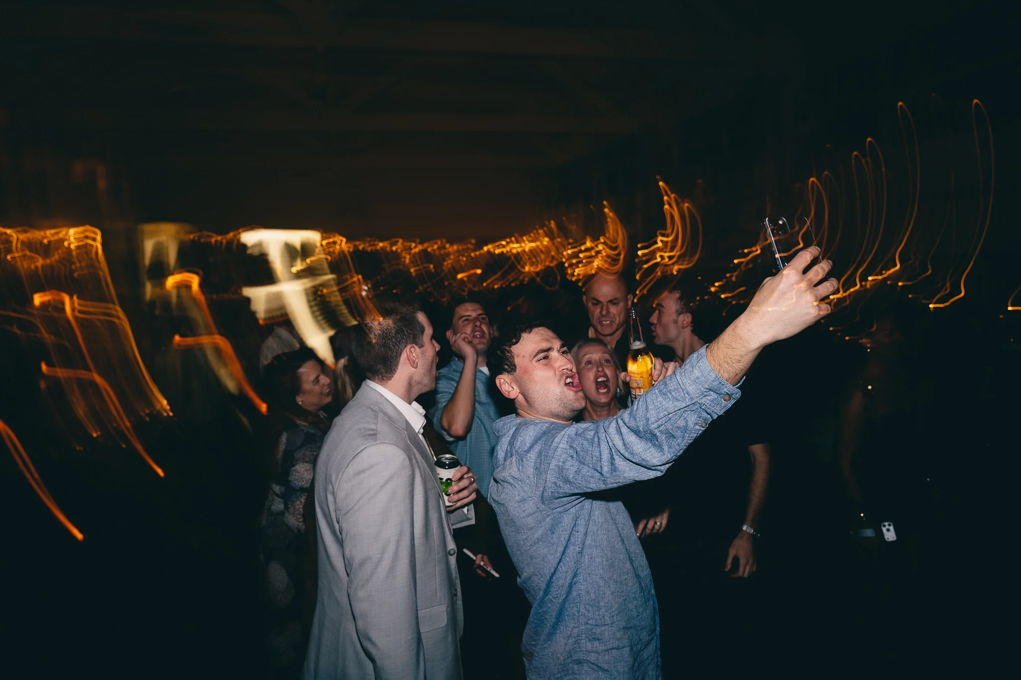 People at a night party taking a selfie with a smartphone.