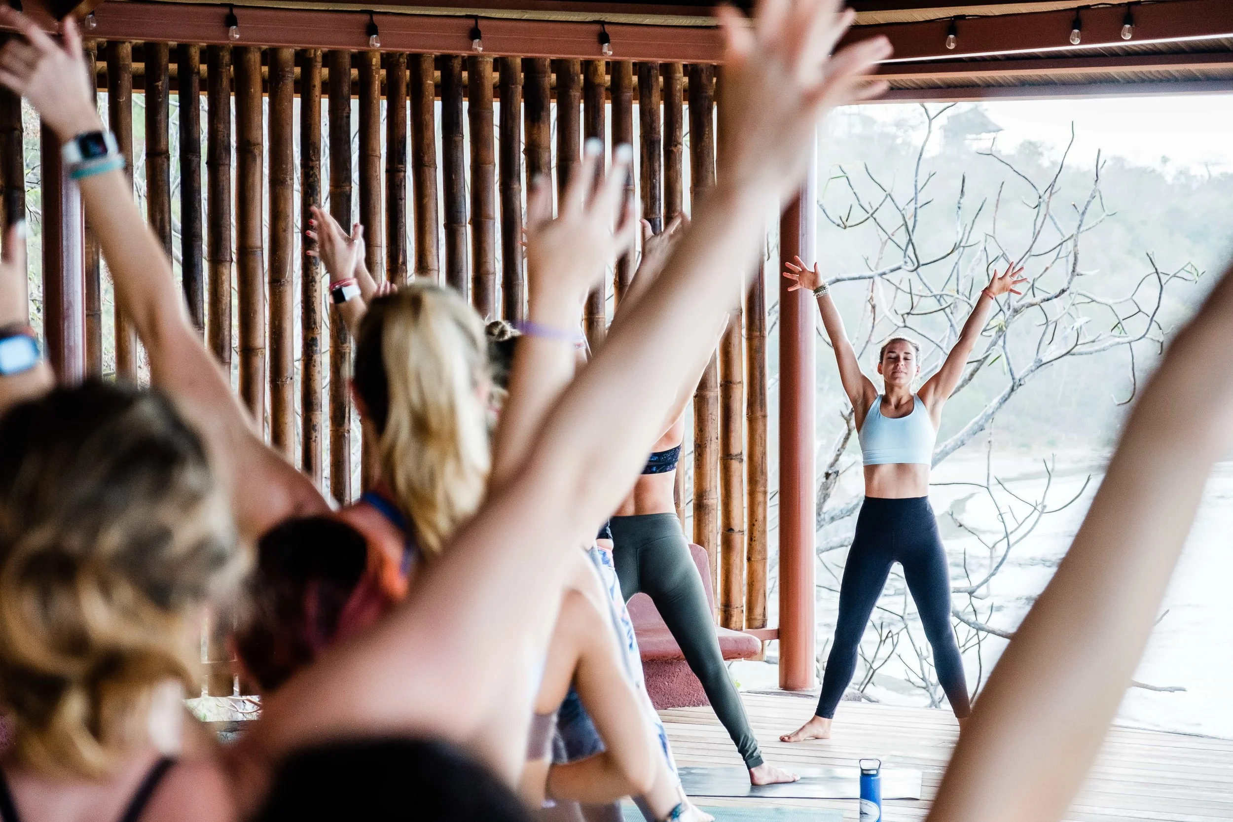 A beautiful yoga studio filled with students, Sarah leads the class in a star pose.