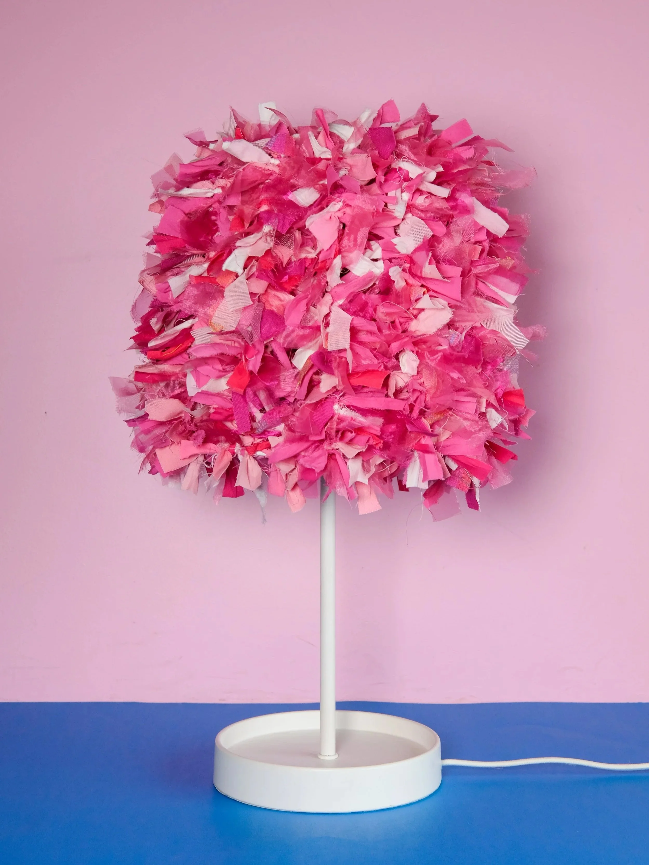 Photograph of a white lamp base and pink ruffled lamp shade made with recycled scrap fabric materials