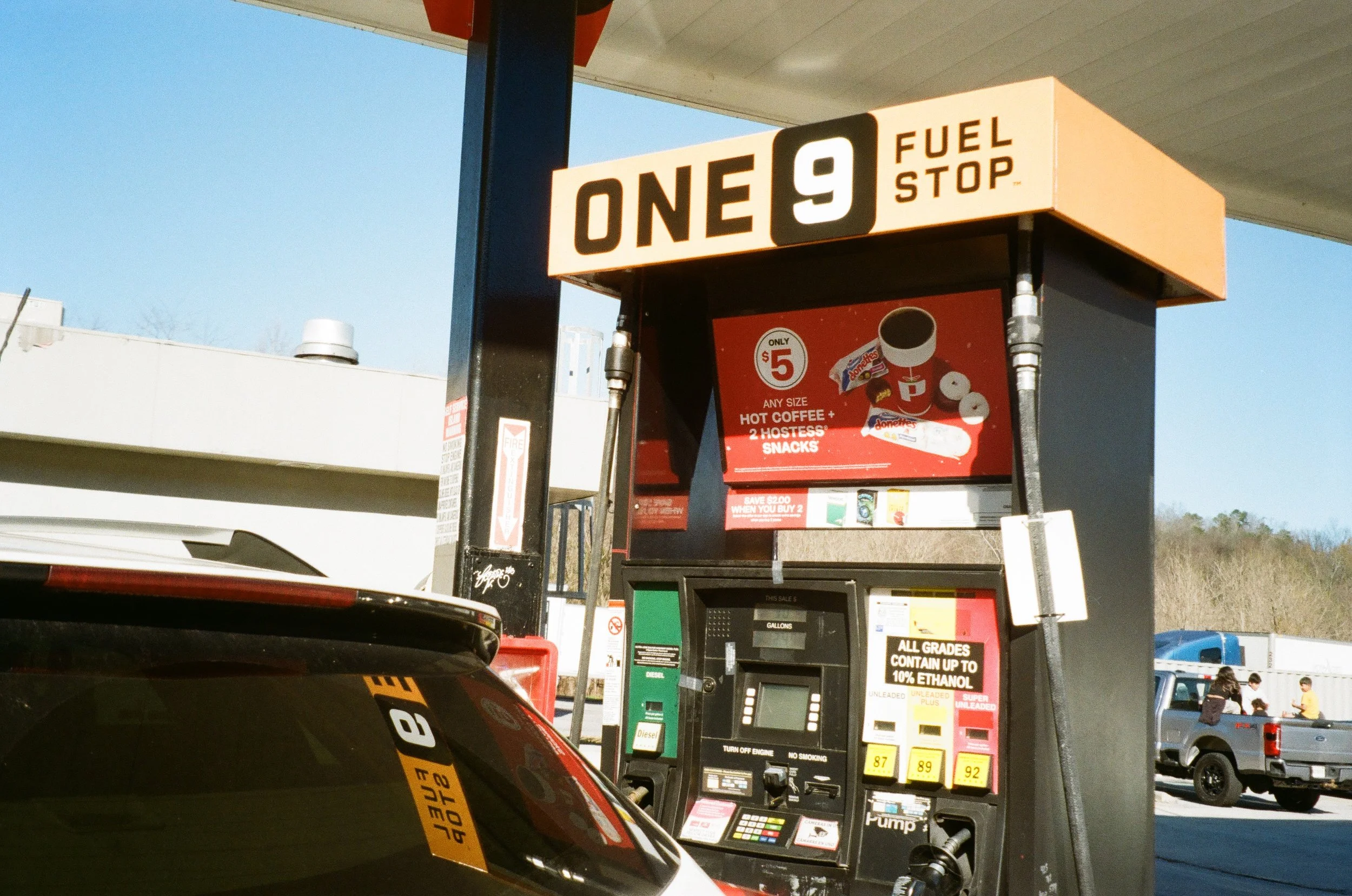 A film photo of a gas station pump with signage indicating the price of regular fuel at per gallon. 