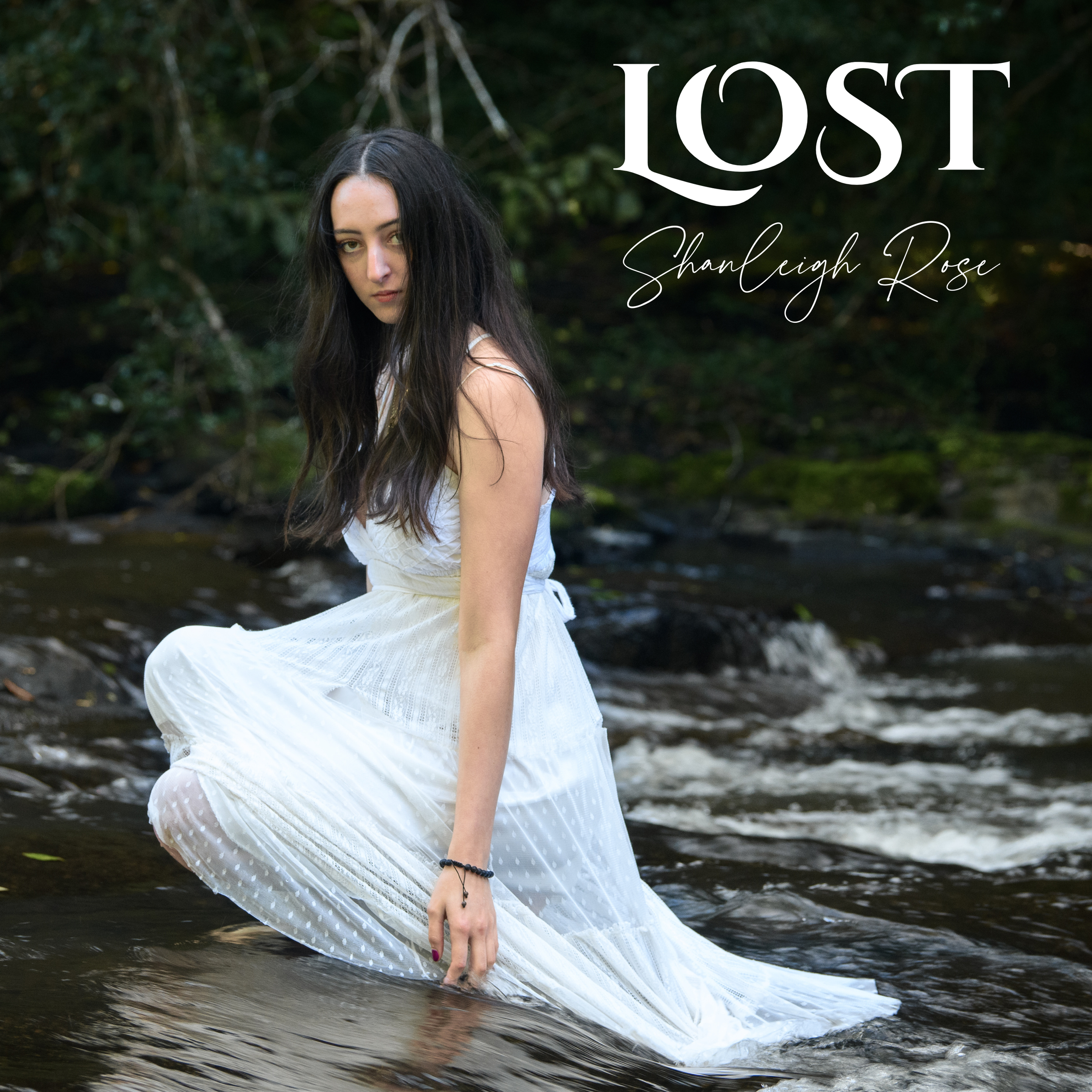 "Lost" Cover Art. Shanleigh rose a white dress sitting in a stream with trees in the background, looking at the camera.