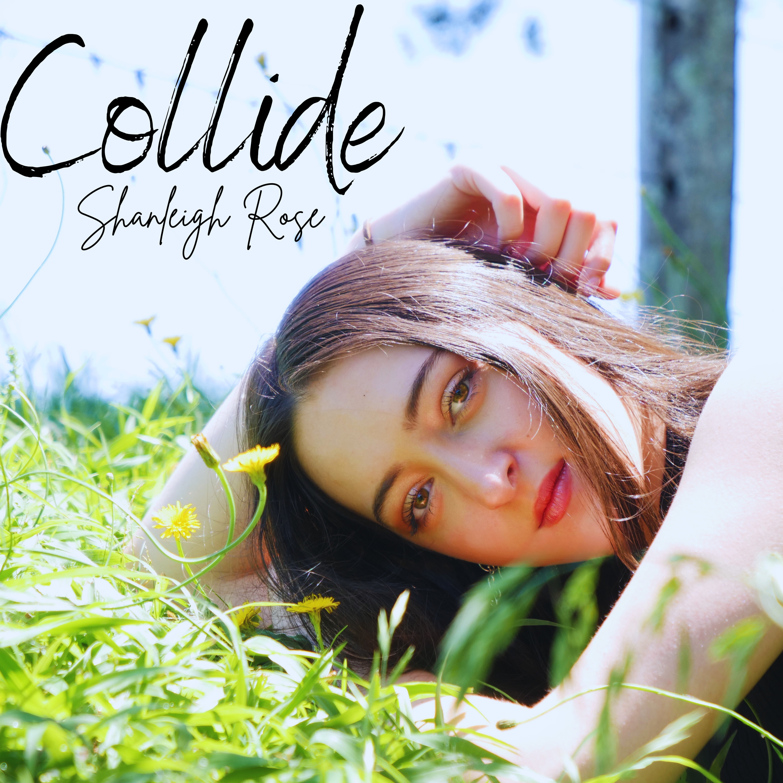 "Collide" Cover Art. Shanleigh Rose lying in a field of green grass and yellow flowers, with her head resting on the ground and her hand touching her hair, under a bright blue sky.