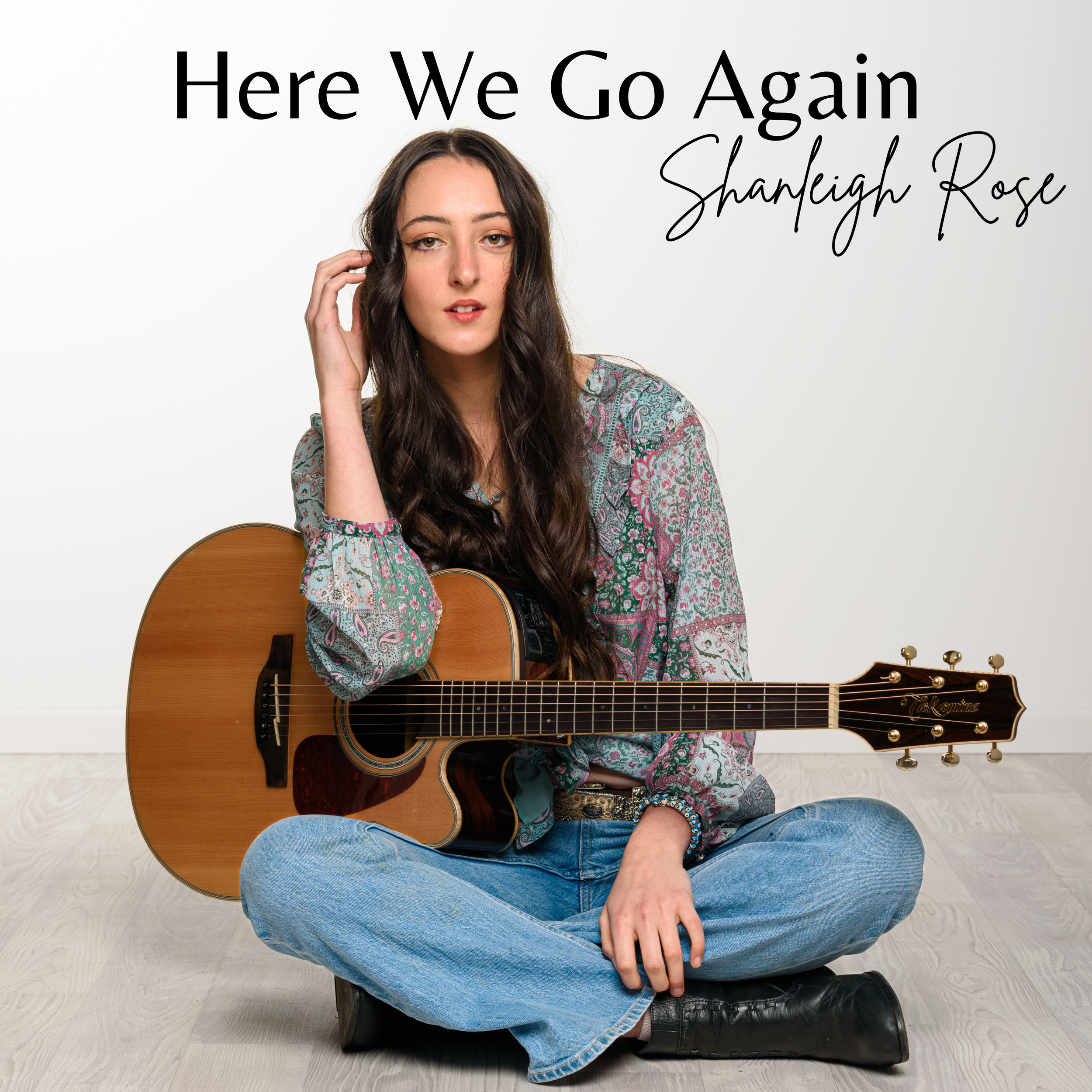 "Here We Go Again" Cover Art. Shanleigh Rose sitting cross-legged on the floor, holding an acoustic guitar, with text 'Here We Go Again' and 'Shanleigh Rose' written on the wall behind her.