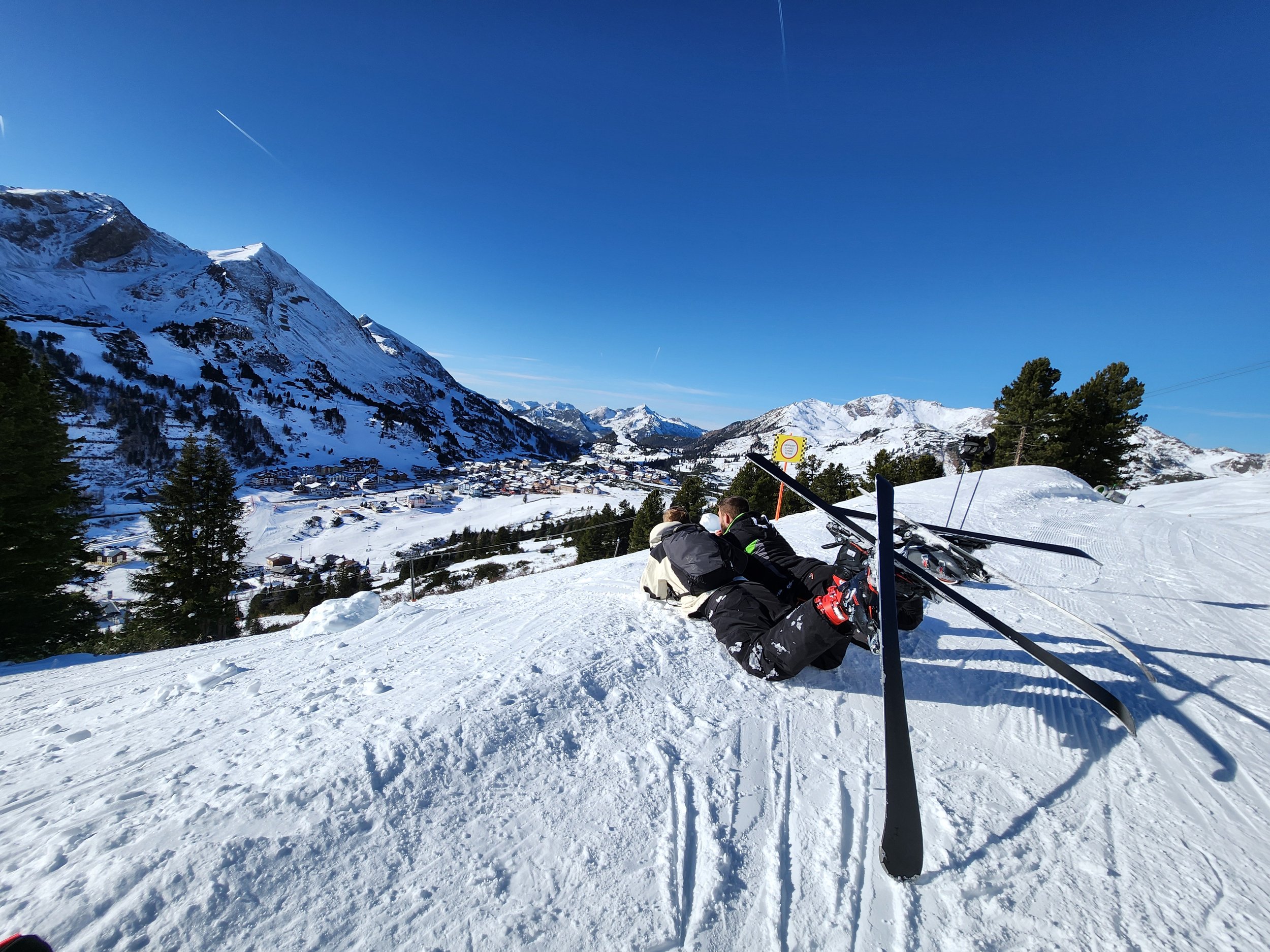 Two boys skiing down a snowy mountain with expansive alpine views, capturing the joy of family travel and adventure