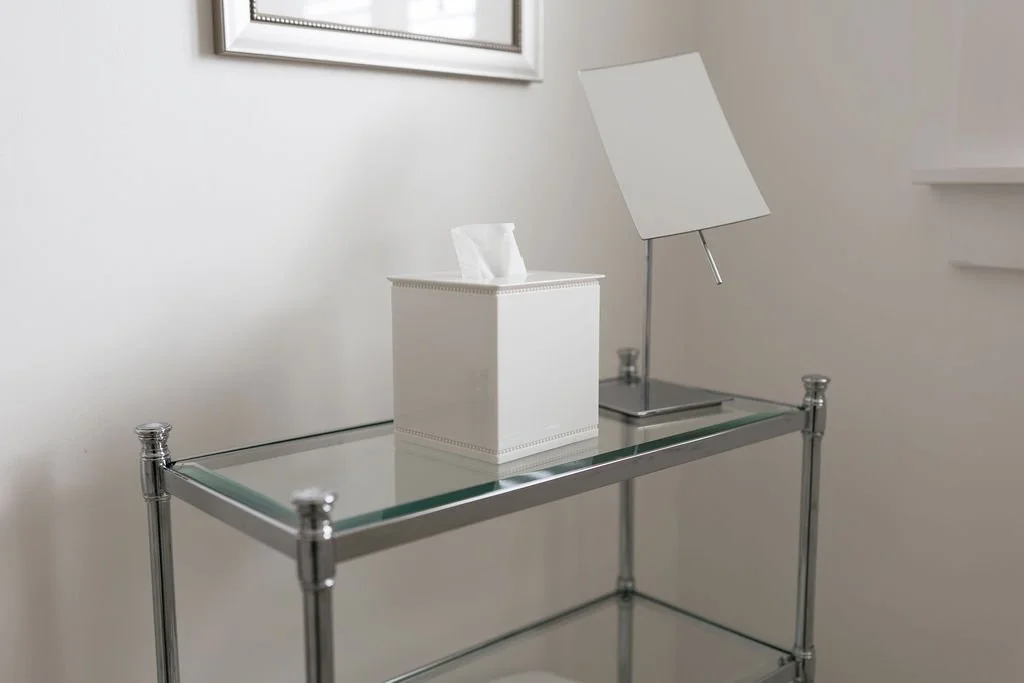 Decorative glass table with a tissue box, a modern desk lamp, and a framed picture on the wall behind.