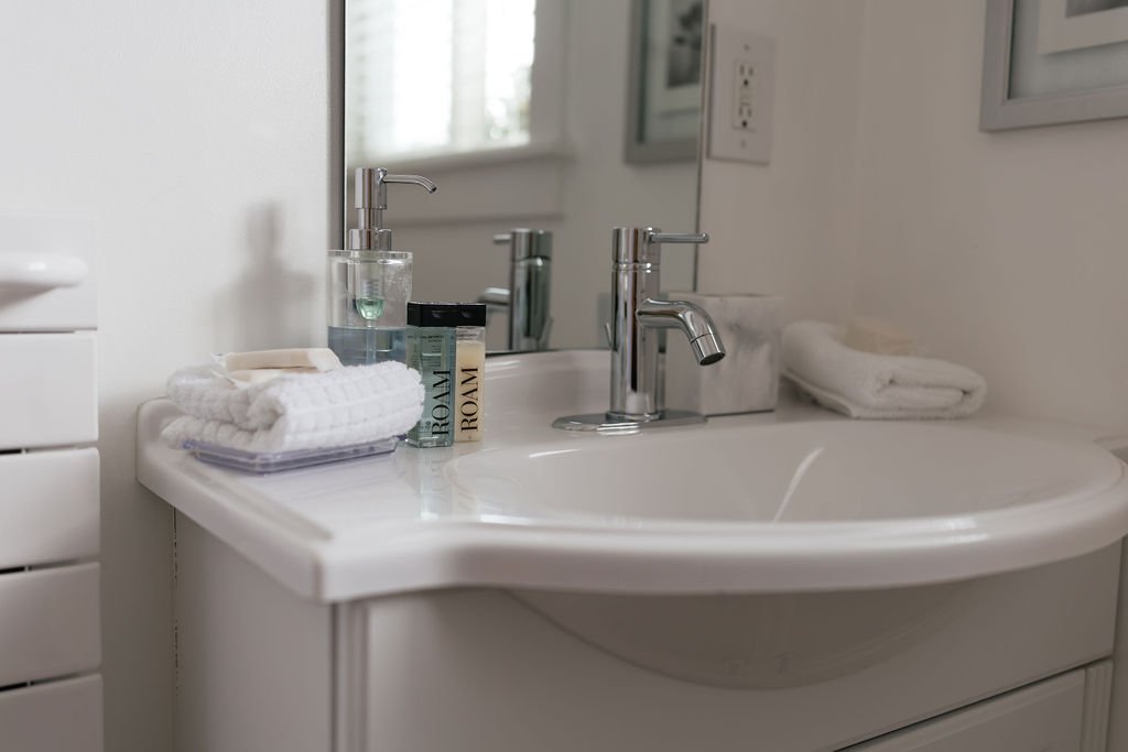 Bathroom sink with toiletries, towels, and a mirror.