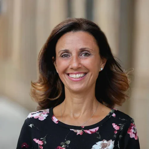 smiling woman with brown shoulder length hair and black floral top