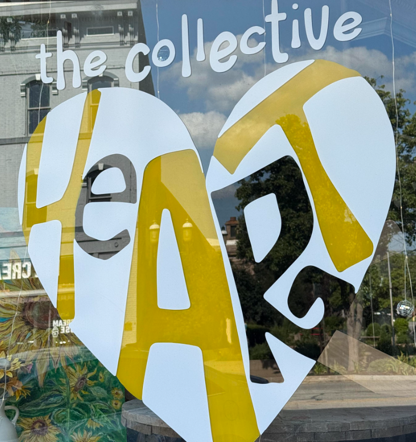 Sign reading 'the collective' above a heart-shaped cutout with the word 'READ' inside, displayed on a glass window.