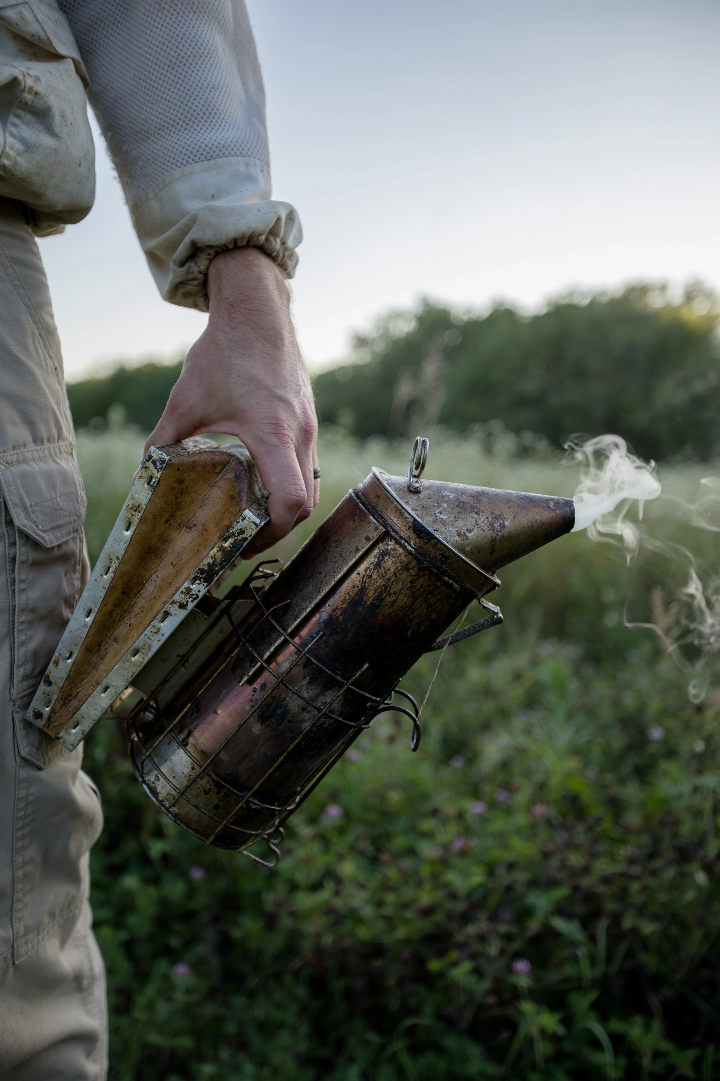 A person holding a makeshift rocket launcher with a smoking rocket in a grassy field during daylight.