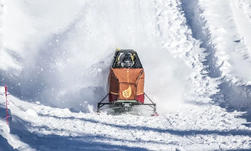 A snowmobile moving through deep snow on a snowy landscape.