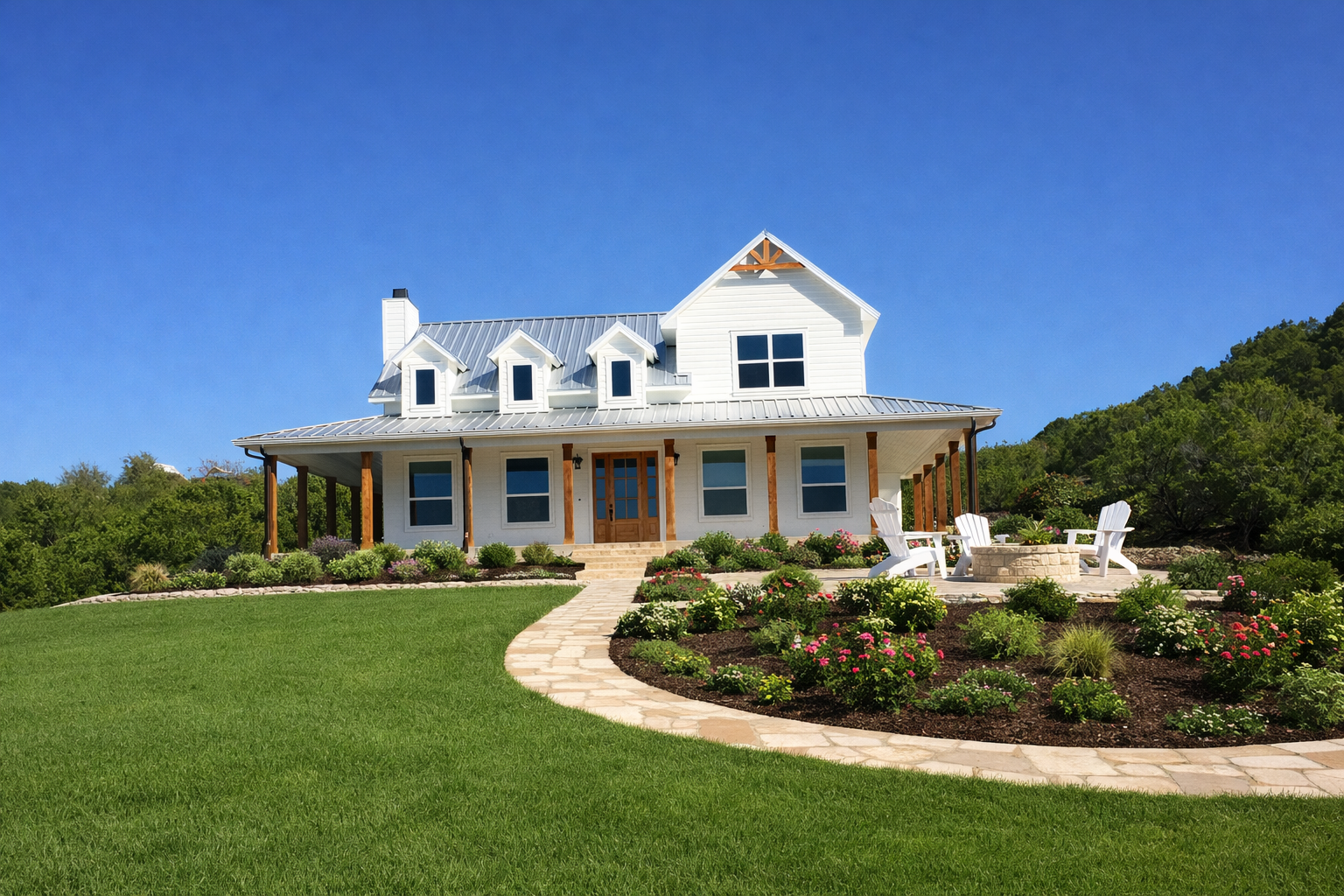 White house with metal roof and front porch, surrounded by landscaped garden and lawn, with a clear blue sky and green hills in the background.