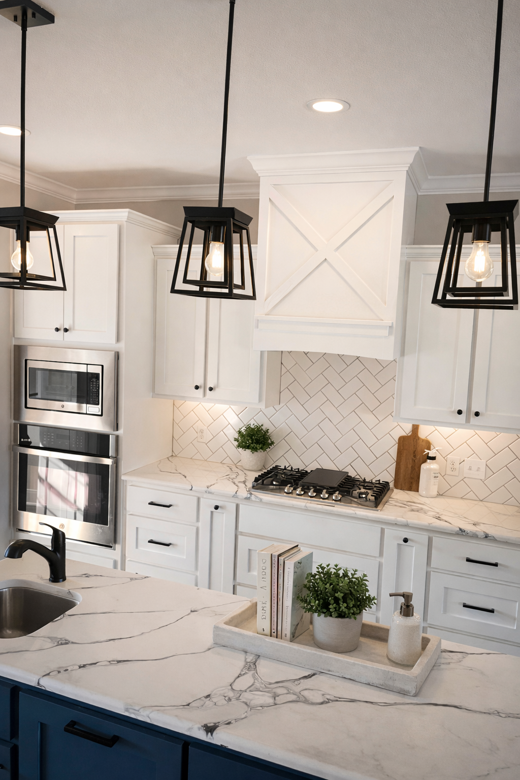 Modern kitchen with white cabinets, marble countertops, and black pendant lights.